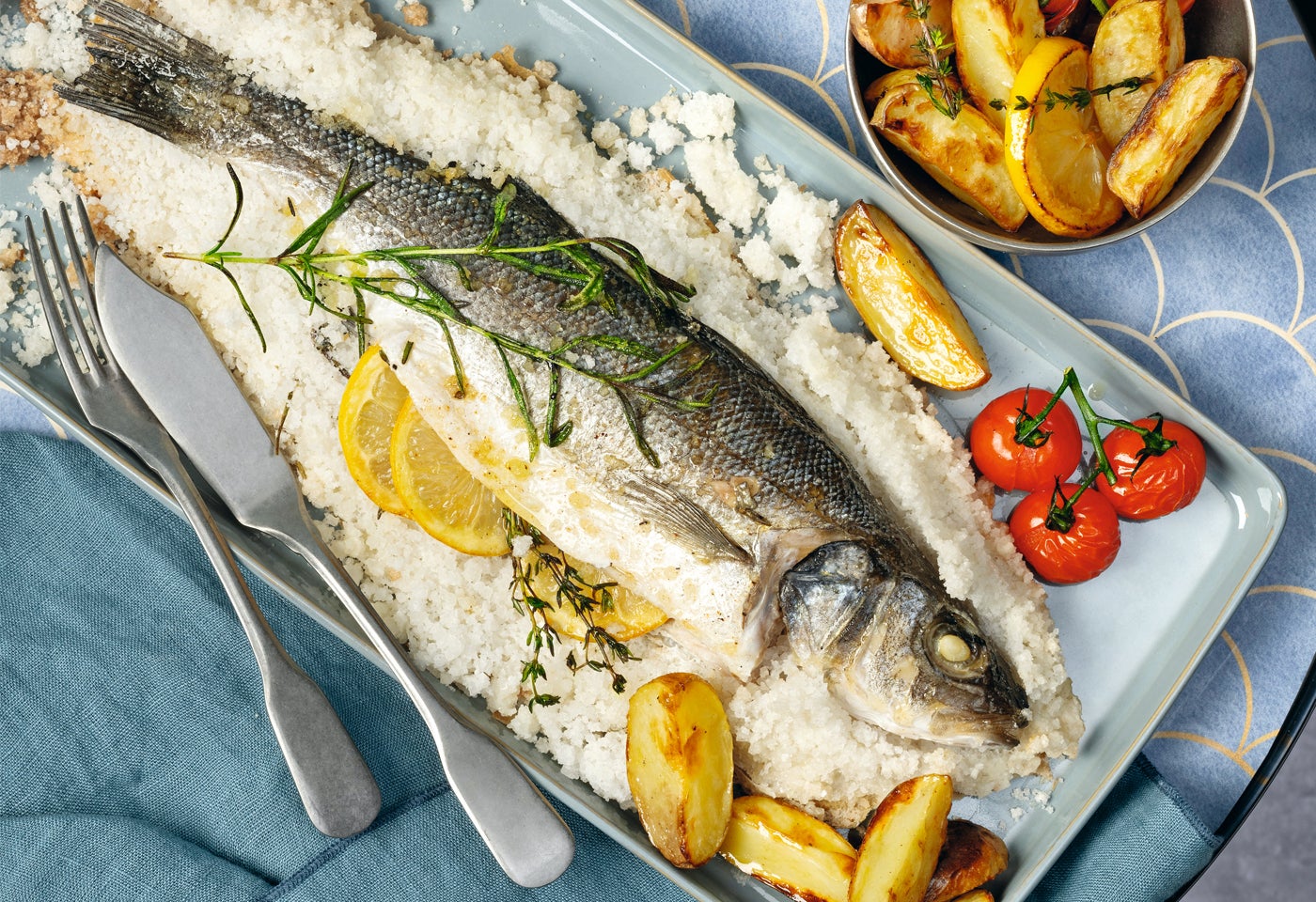 Wolfsbarsch in Kräuter-Salzkruste mit Ofentomaten und Ofenerdäpfeln | BILLA
