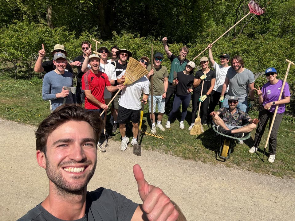 Group of people in nature smiling and cheering with tools in their hands.