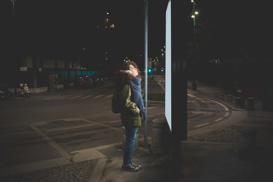 A dark scene where a girl looks at a big Out of Home screen.