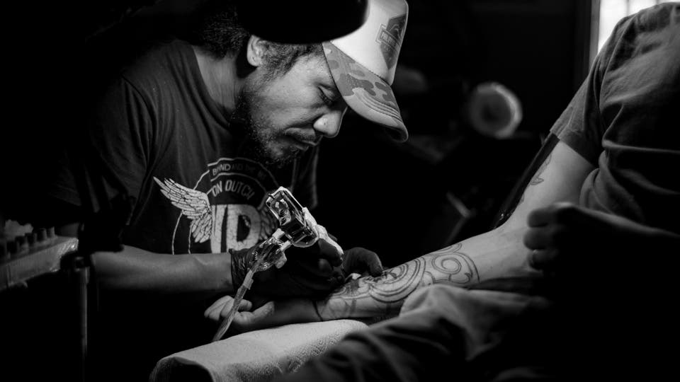 Man tattooing on a person right arm