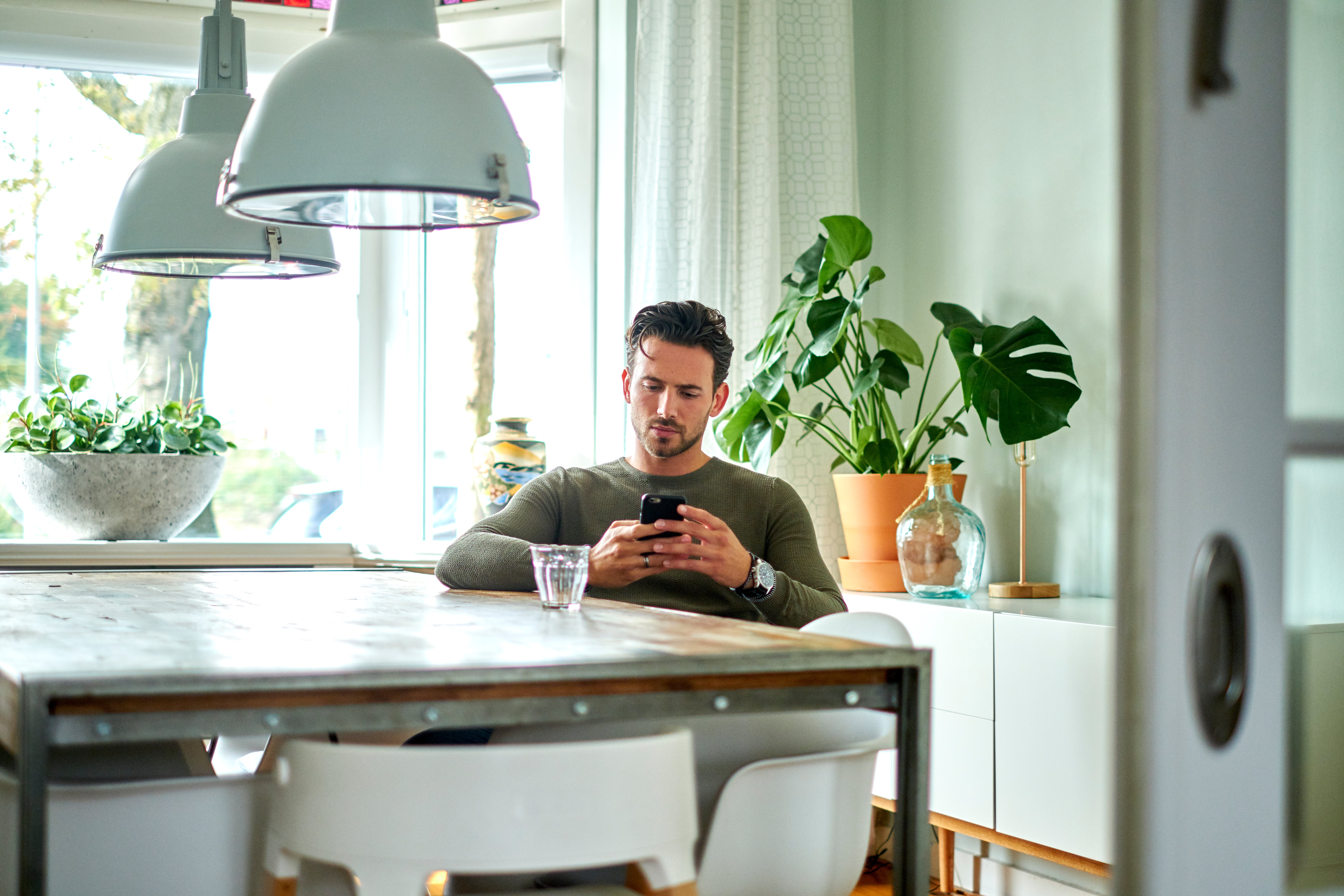 man met telefoon zit aan tafel