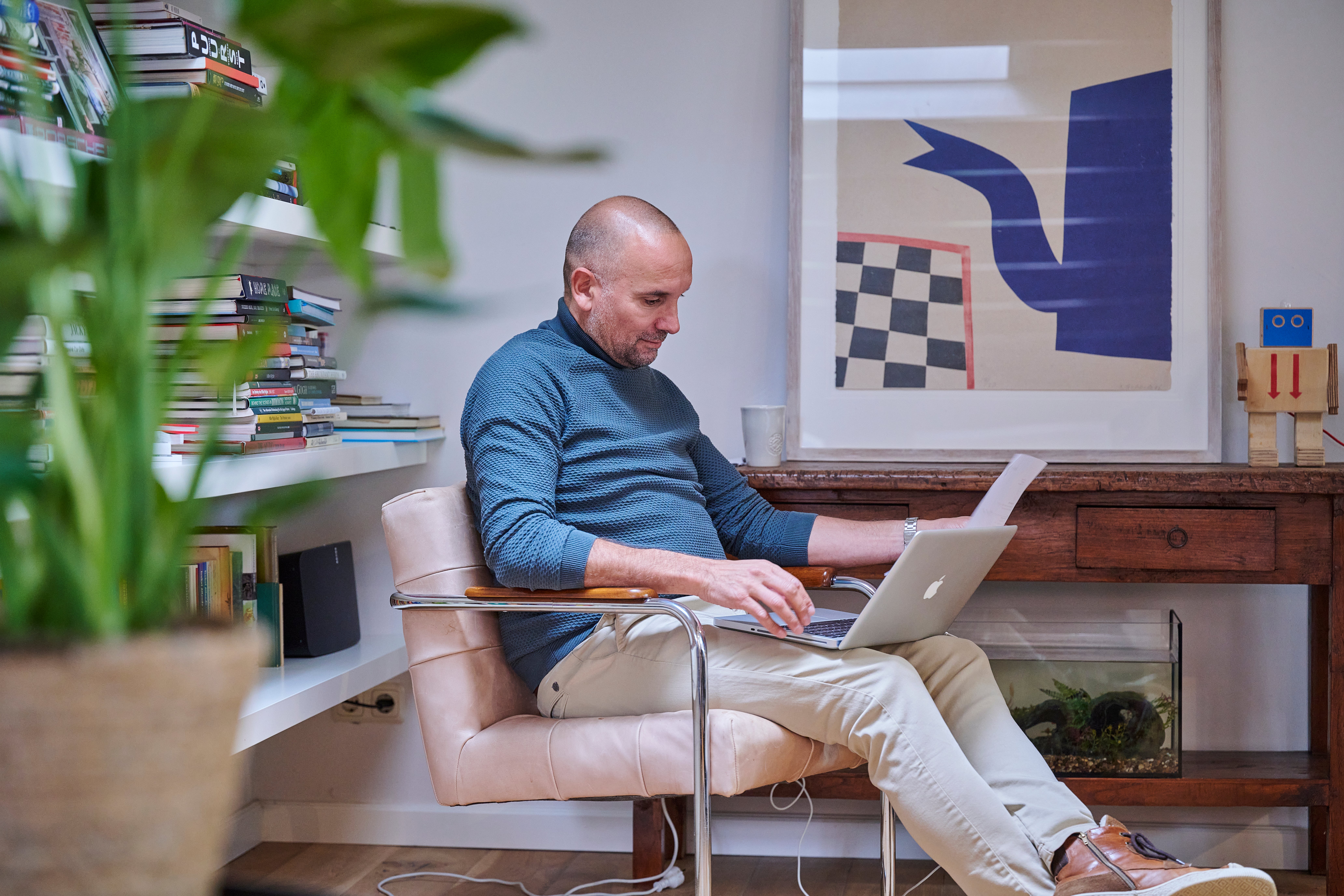 man zit met laptop en papierwerk