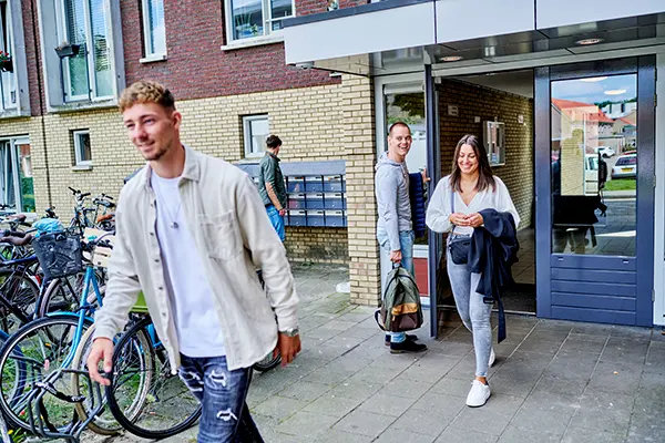jongeman en -vrouw lopen uit ingang appartementencomplex