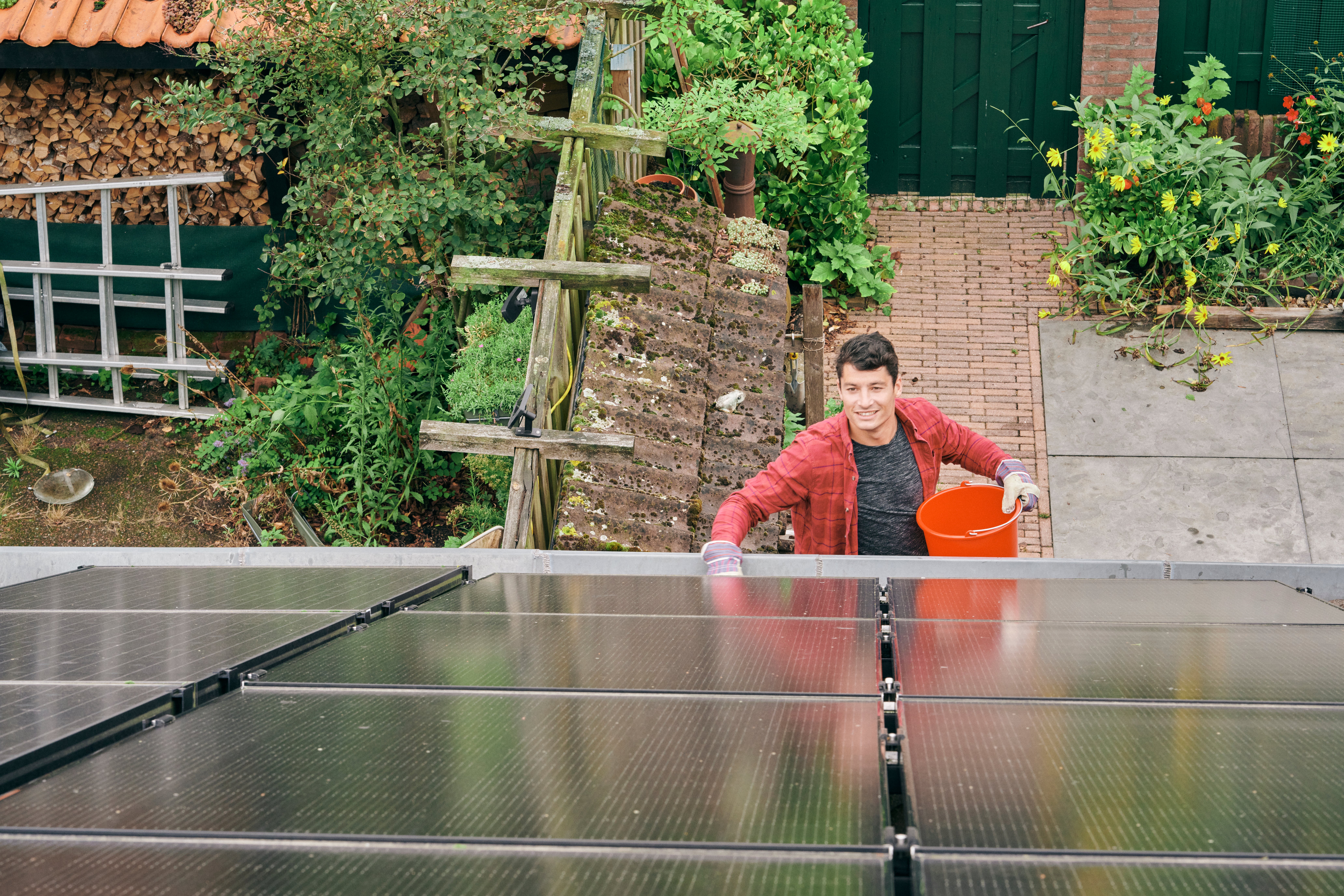 zonnepanelen schoonmaken door man met emmer water