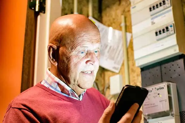 man met telefoon bij meterkast