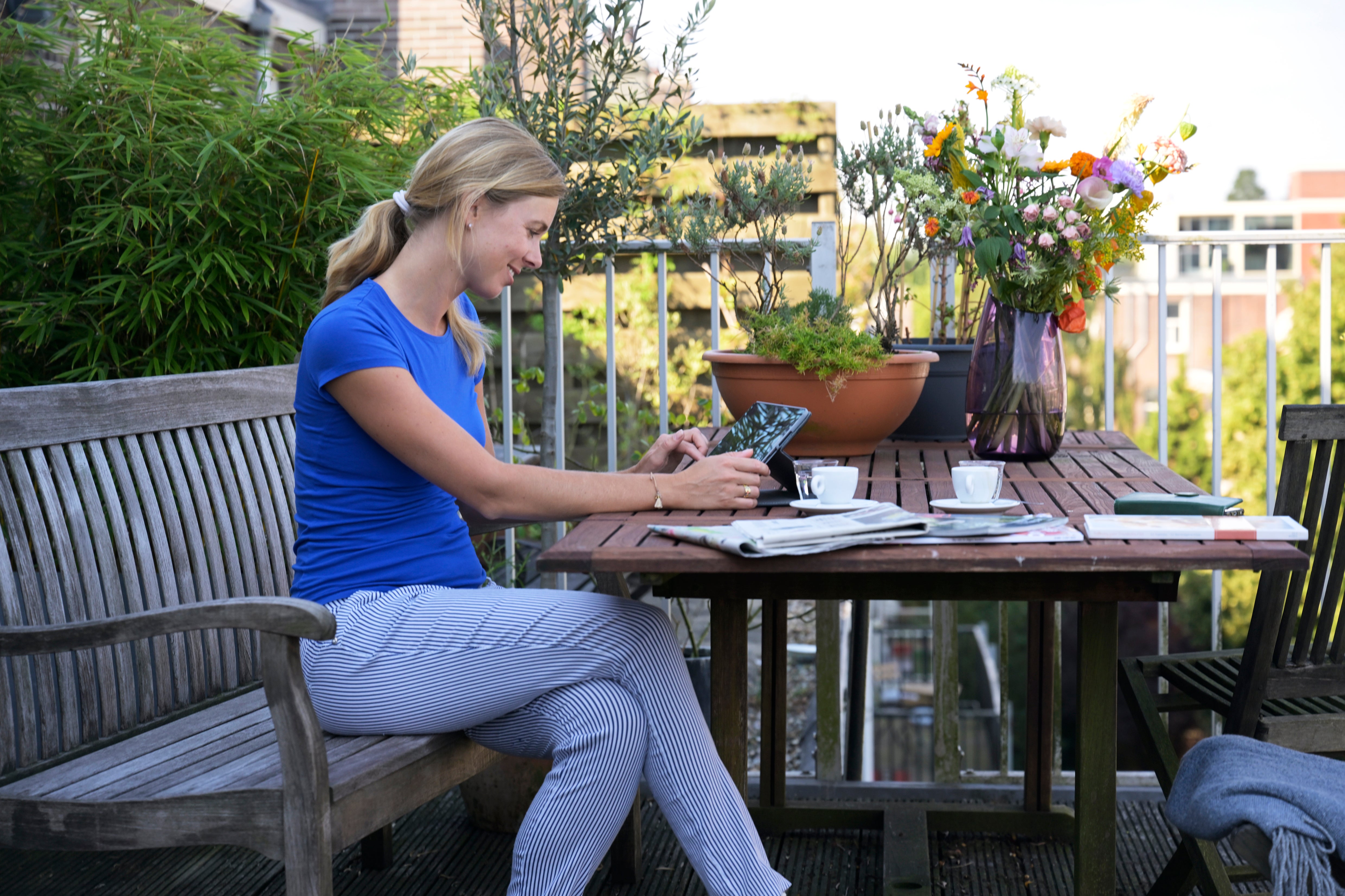 vrouw met tablet drinkt koffie op het balkon