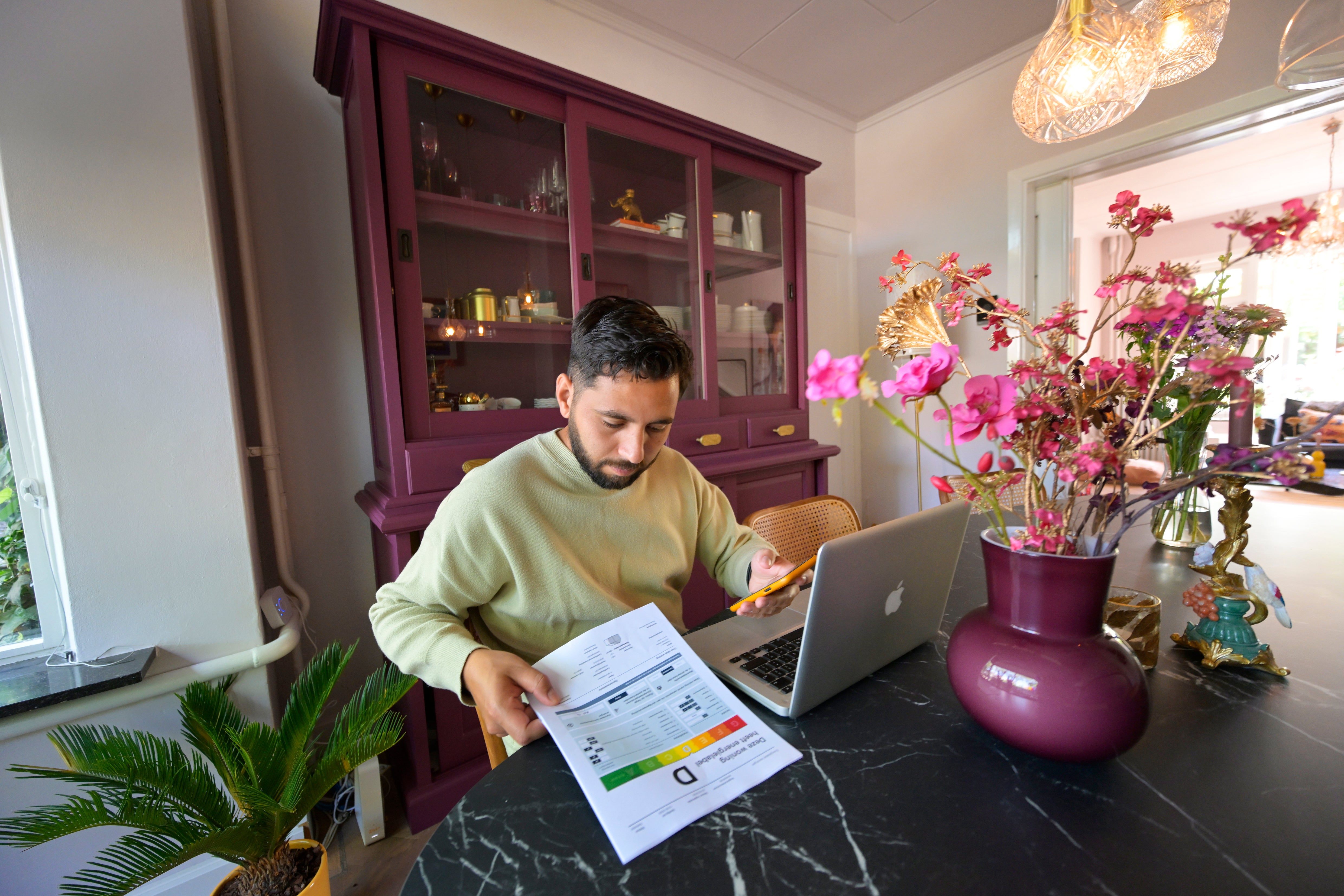 man met rapport energielabel achter laptop aan tafel
