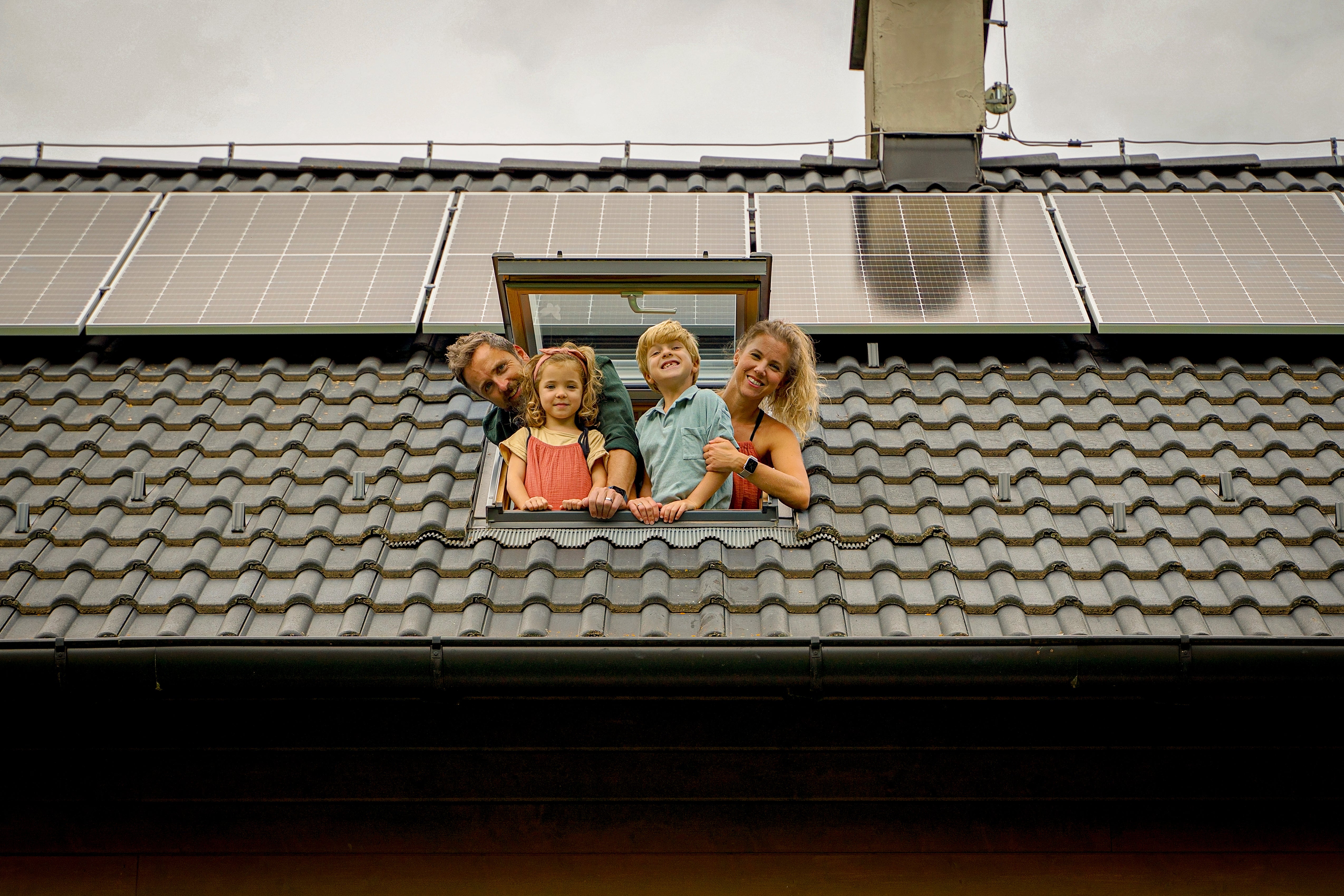 Gezin kijkt uit het dakraam met zonnepanelen.