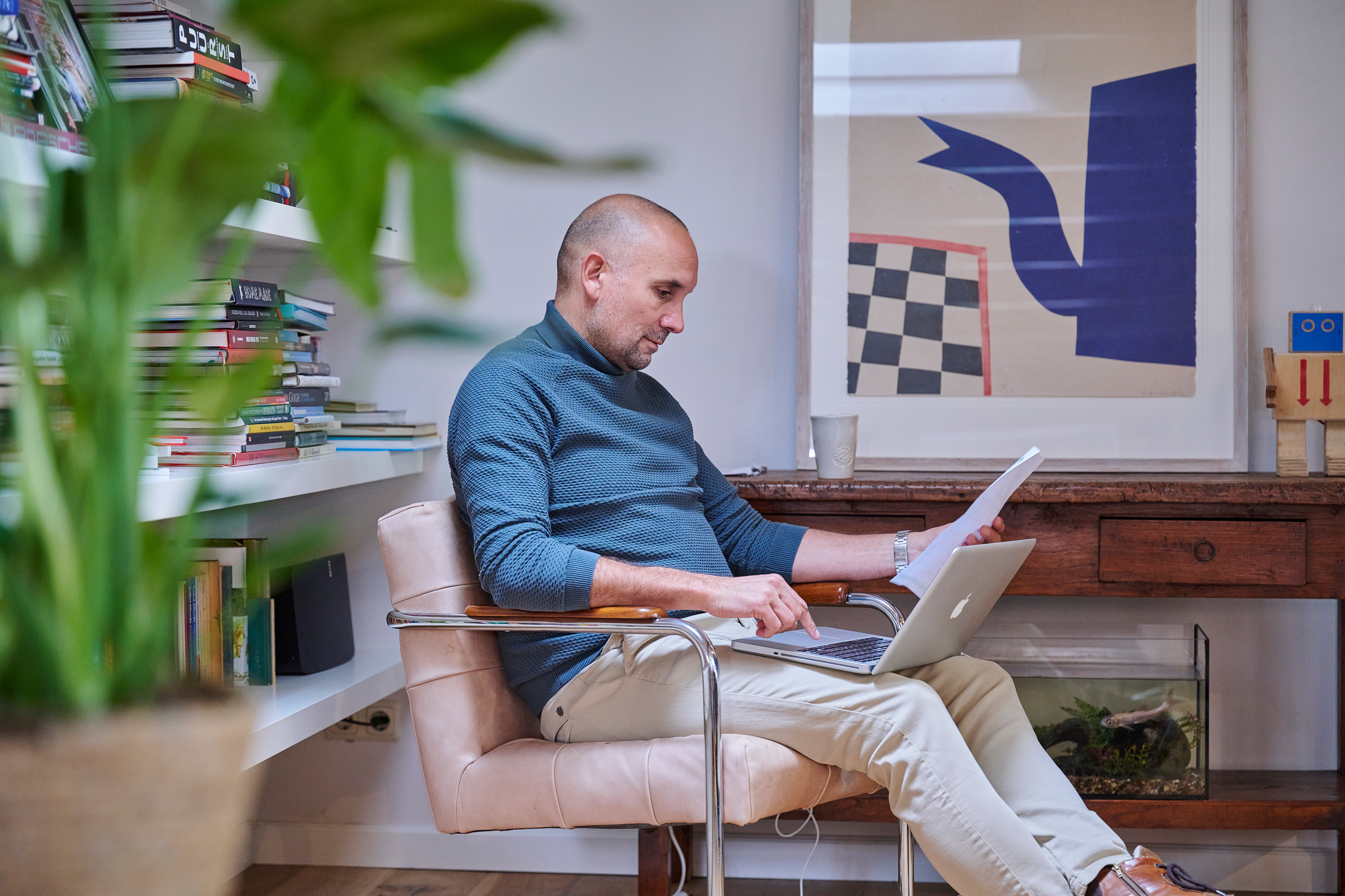 Man zit op een stoel met laptop op schoot.