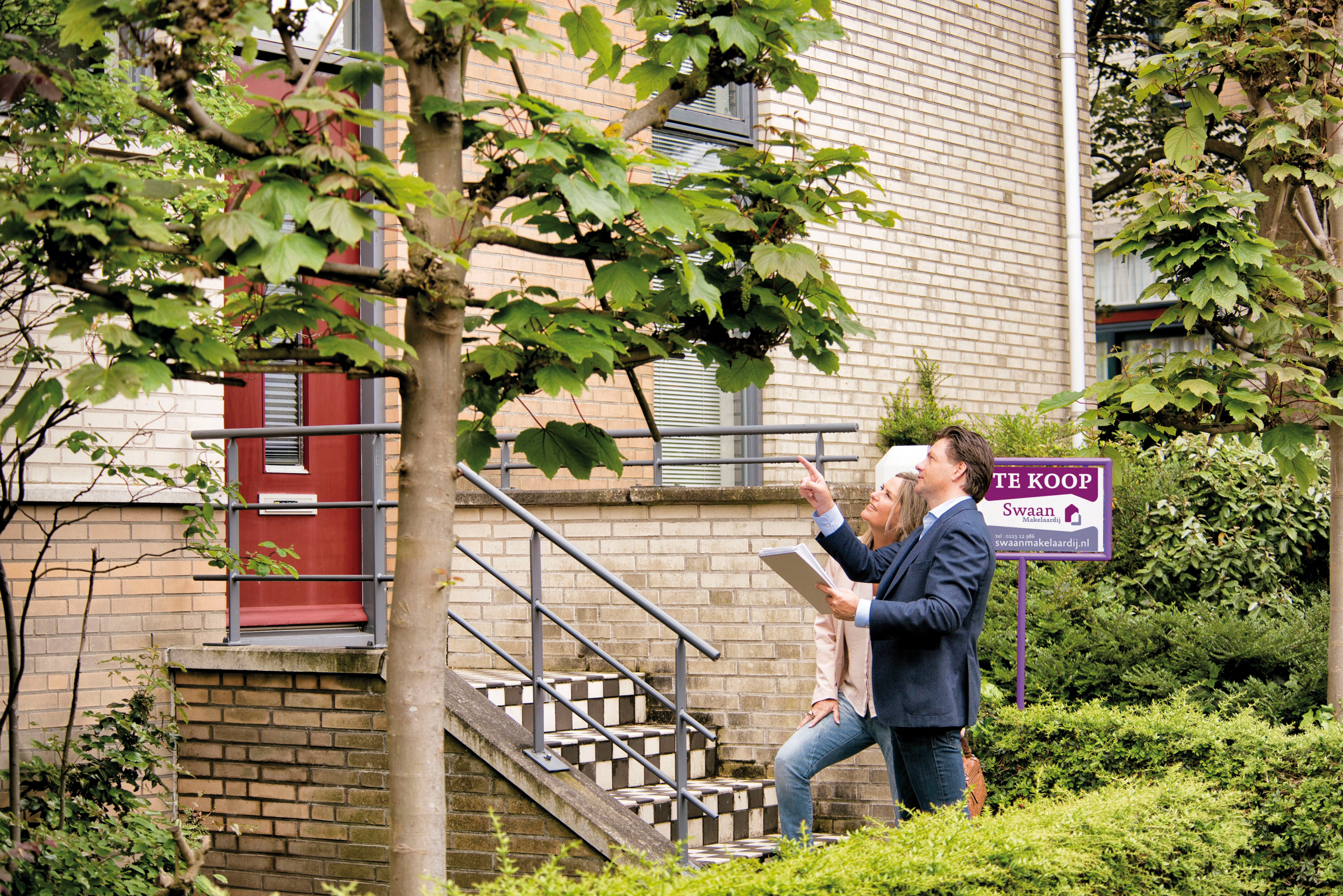 stel met map staat voor koophuis en wijzen ernaar