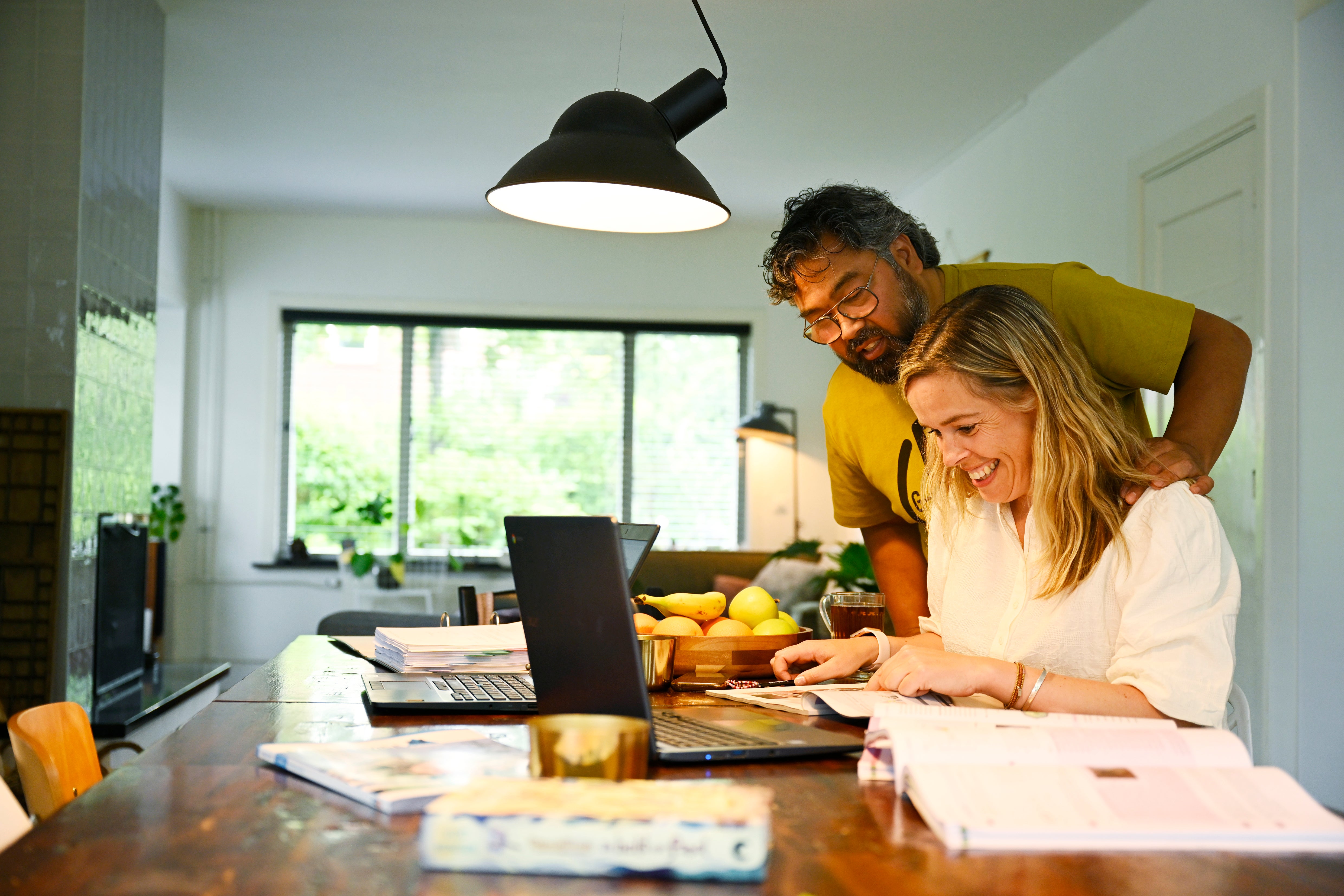 man en vrouw bekijken lachend laptop
