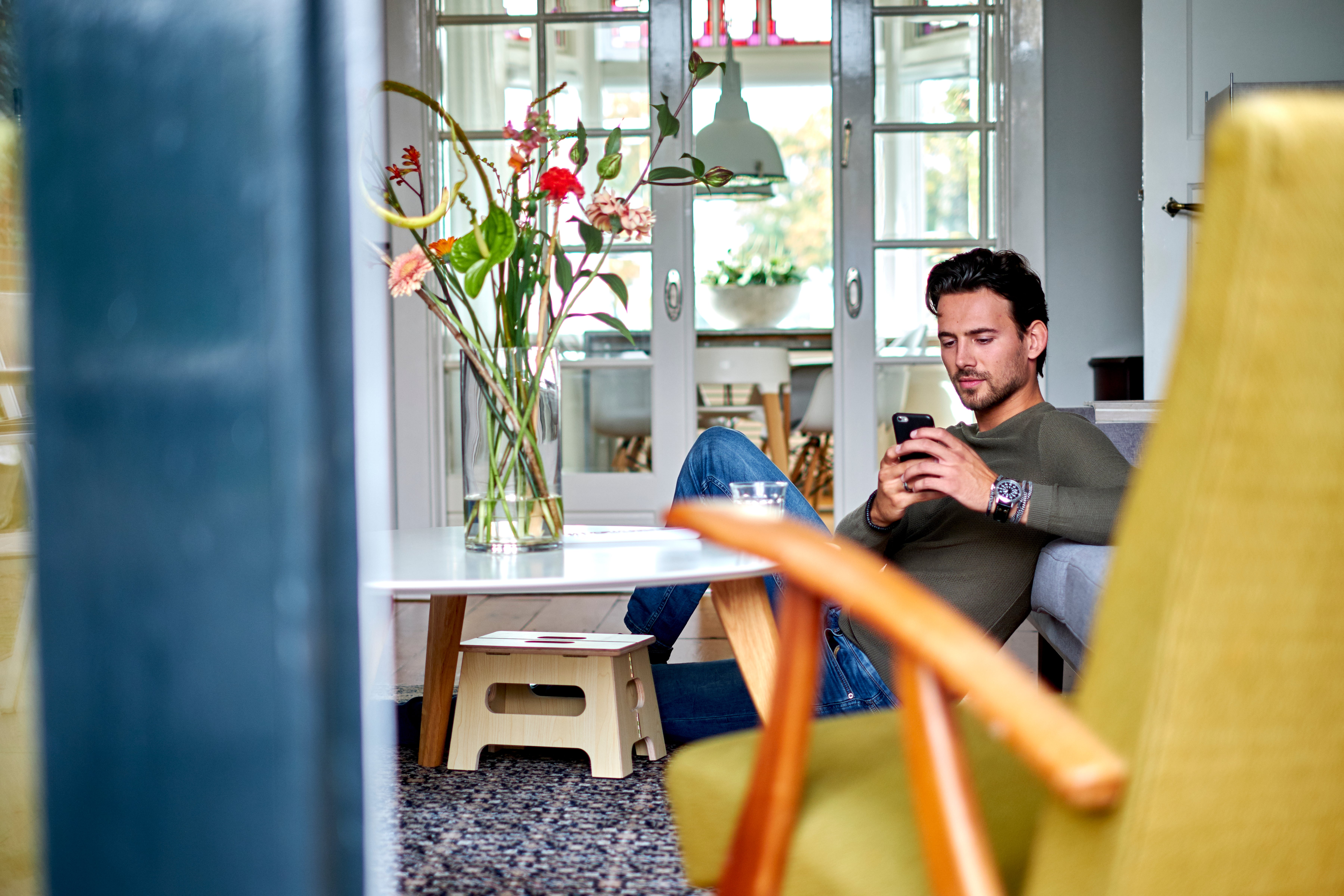 man met telefoon in woonkamer