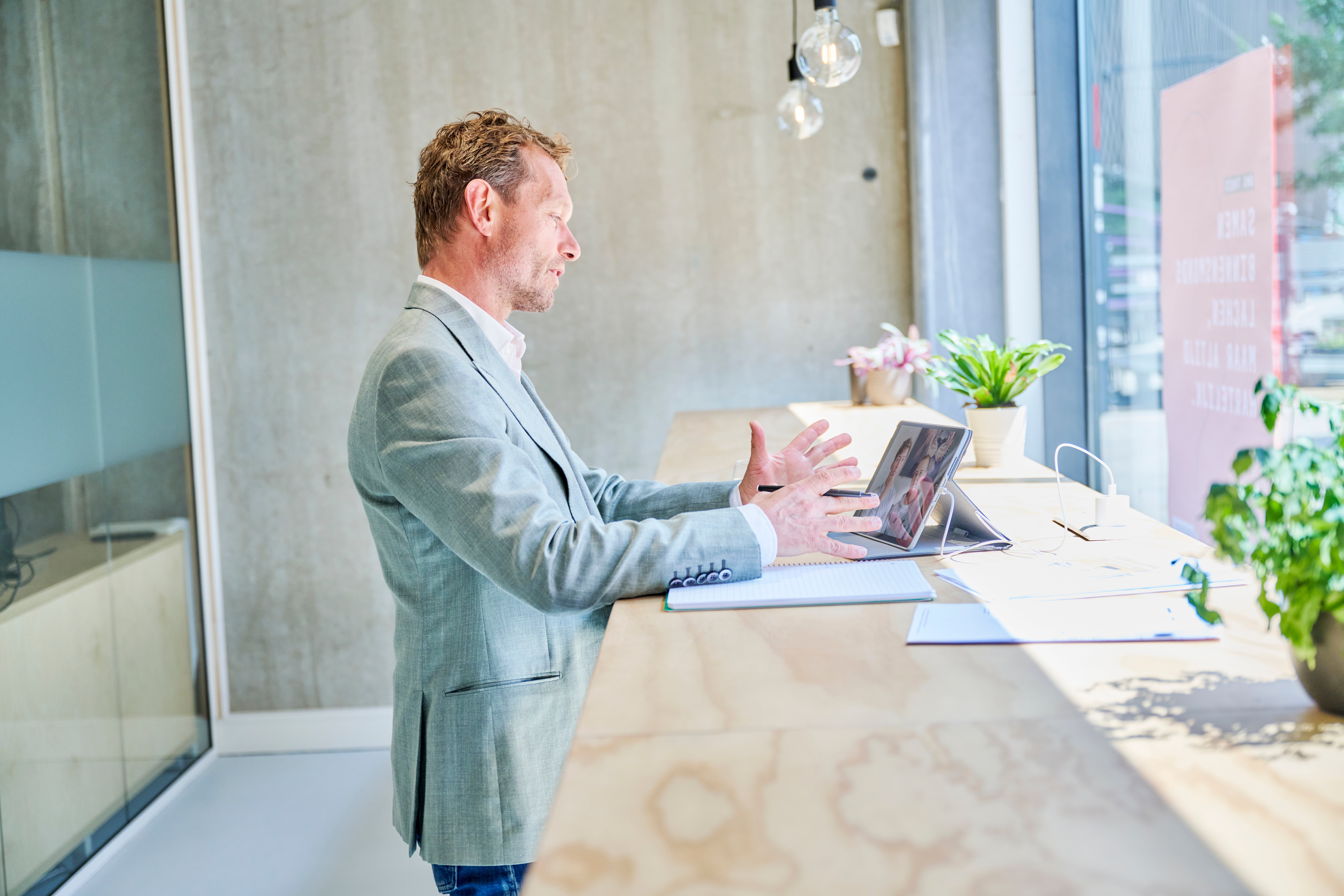 man staat achter bureau en kijkt naar tablet