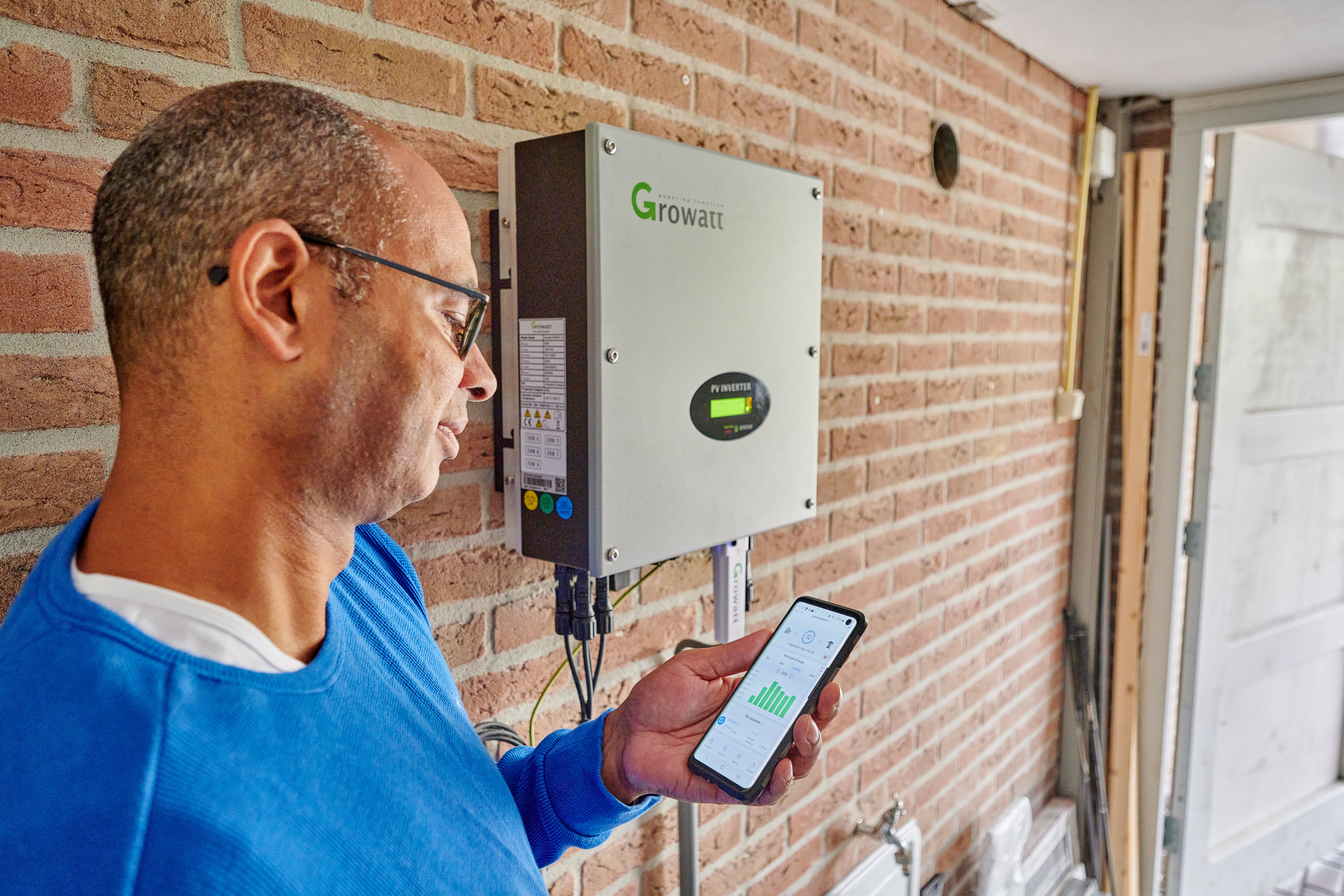 man met telefoon staat bij omvormer