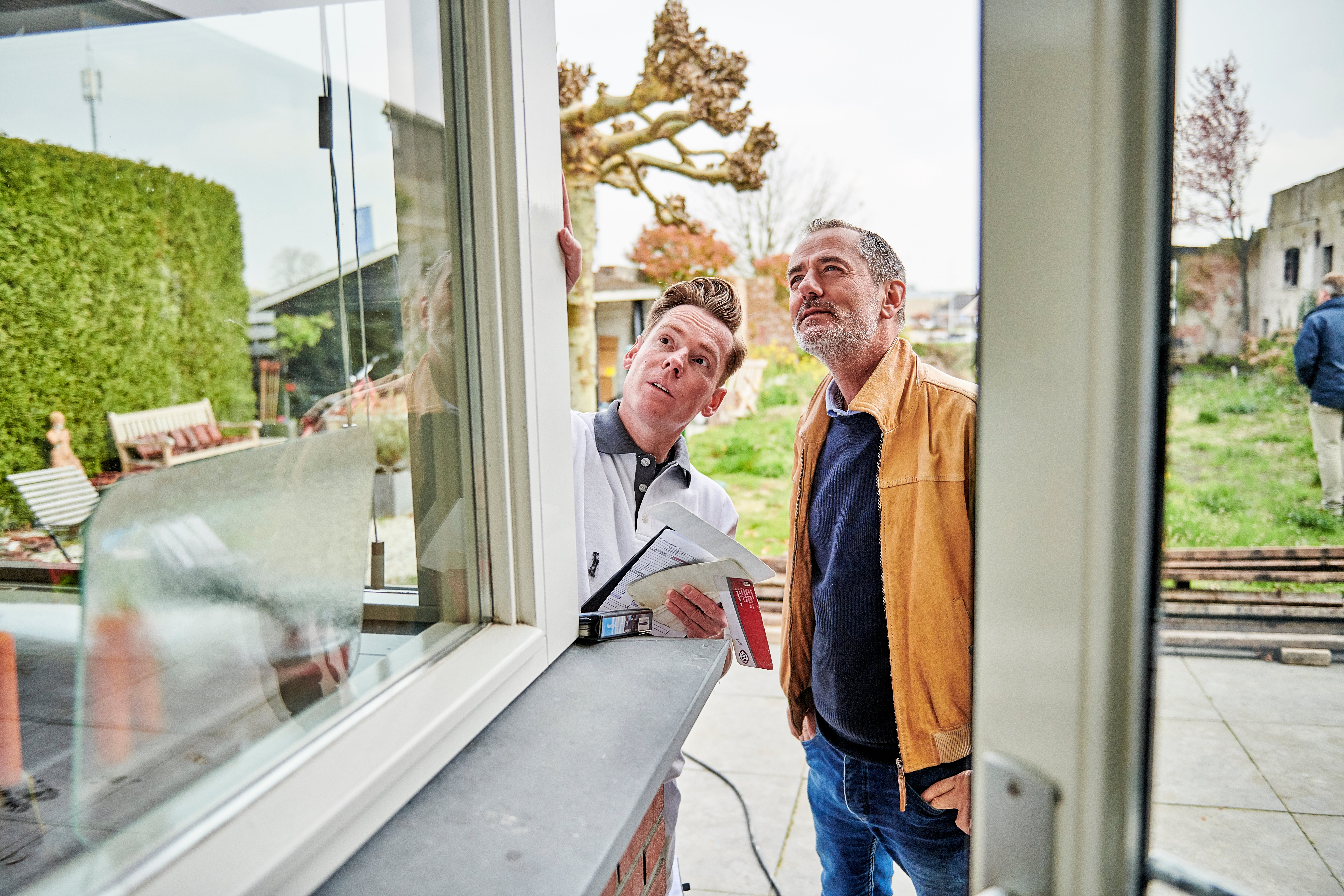 schilder overlegt met man bij kozijn