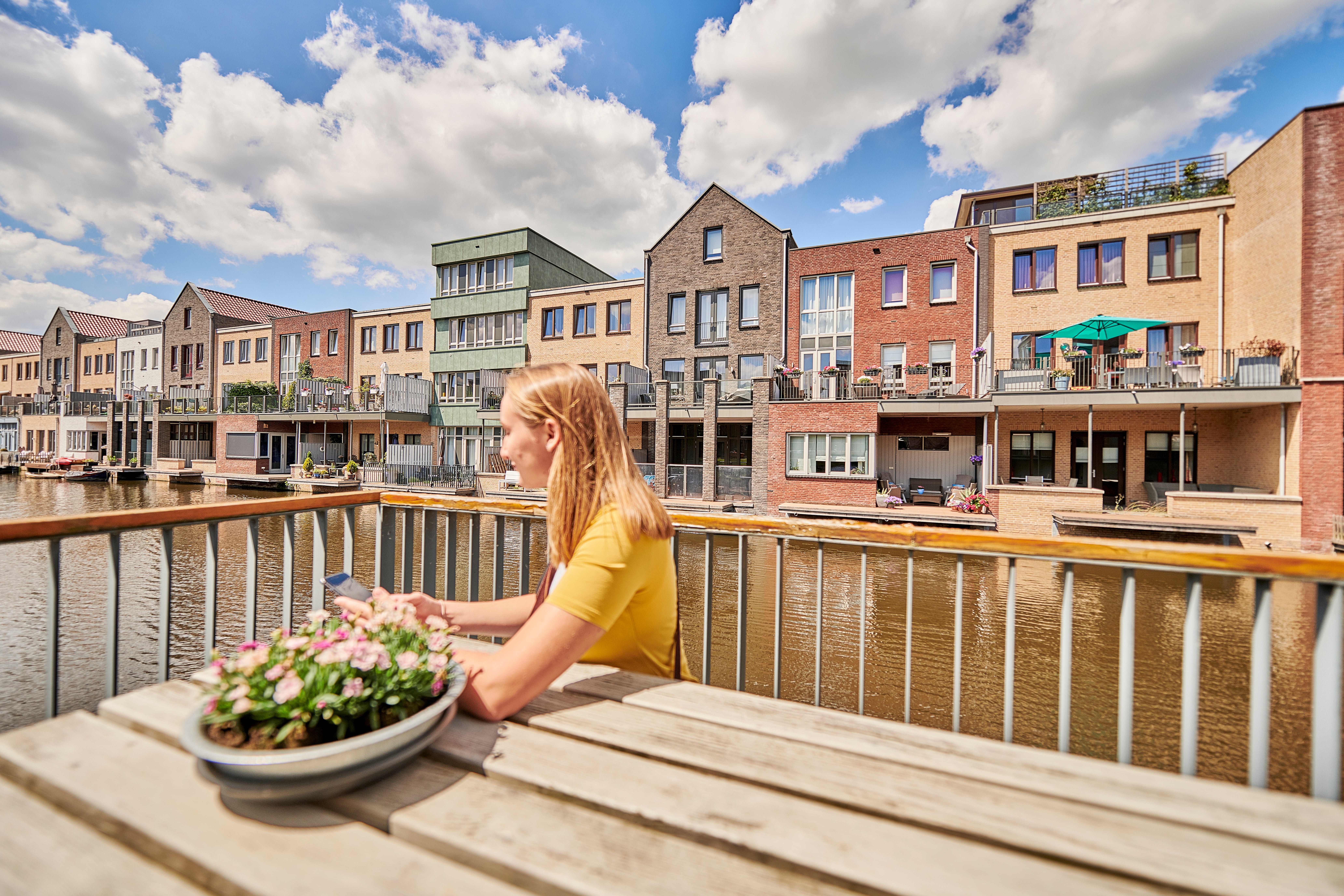 vrouw aan picknicktafel bij gracht in nieuwbouwwijk