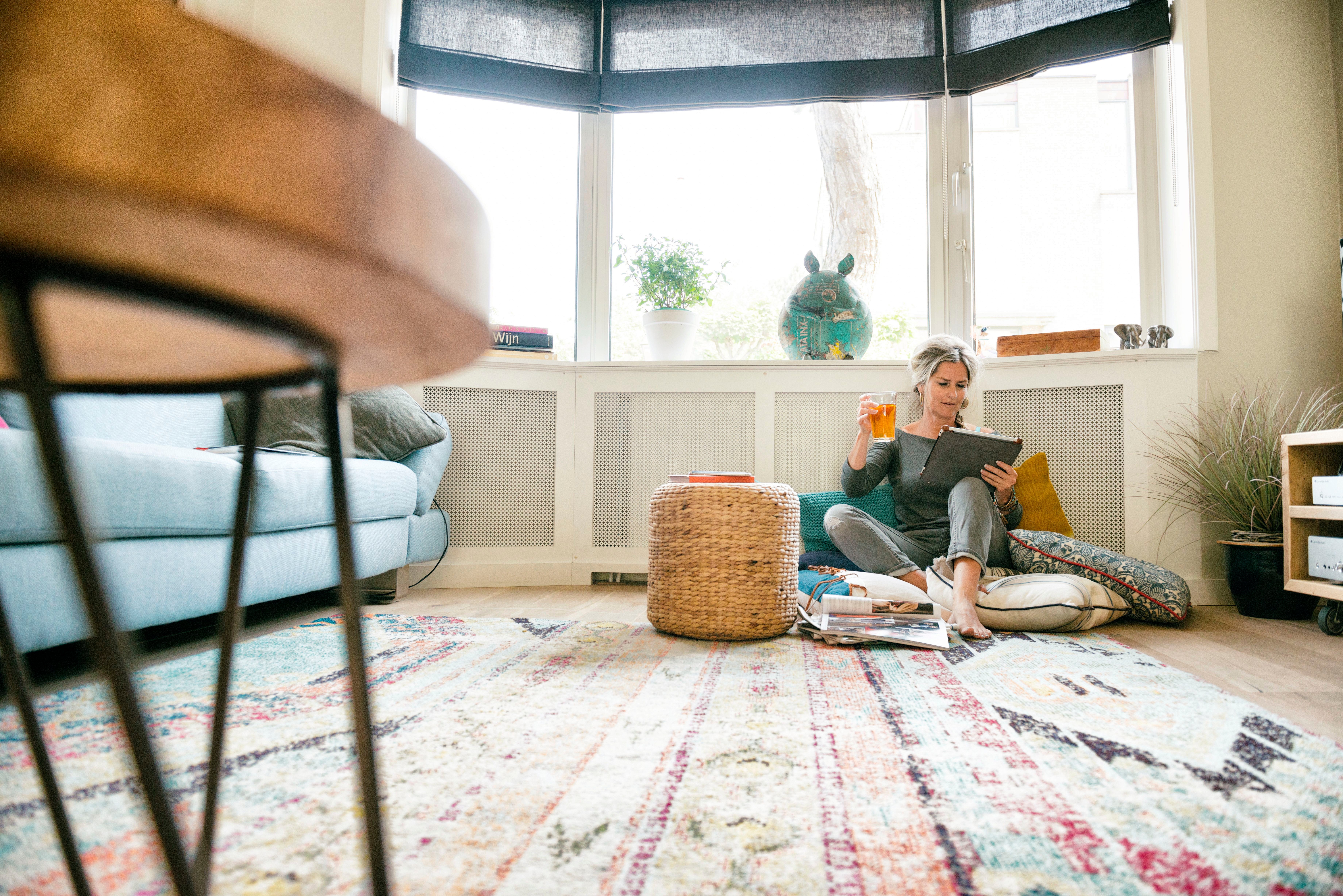vrouw zit op de grond tegen de verwarming met thee en ipad