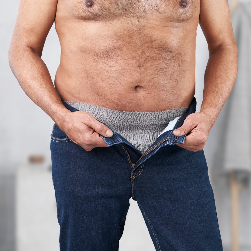 Mann trägt Jeans über Inkontinenzhose