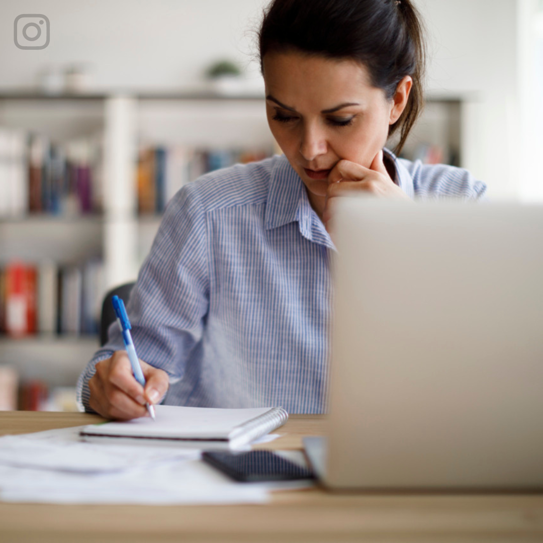 Frau sitzt vor ihrem Laptop und macht sich Notizen