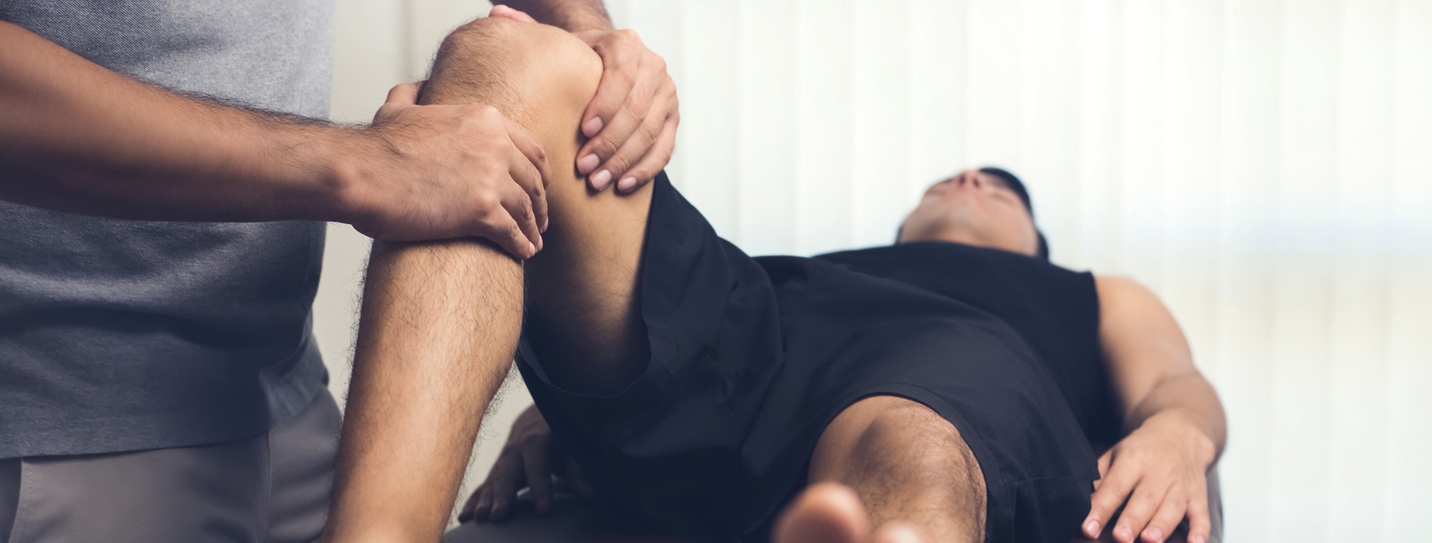 Mann wird am Knie behandelt