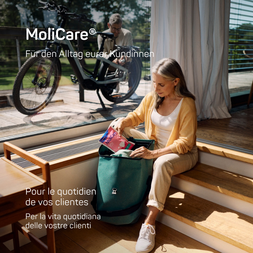 Frau, die ihren Rucksack packt und eine MoliCare® lady Pants Packung in der Hand hält