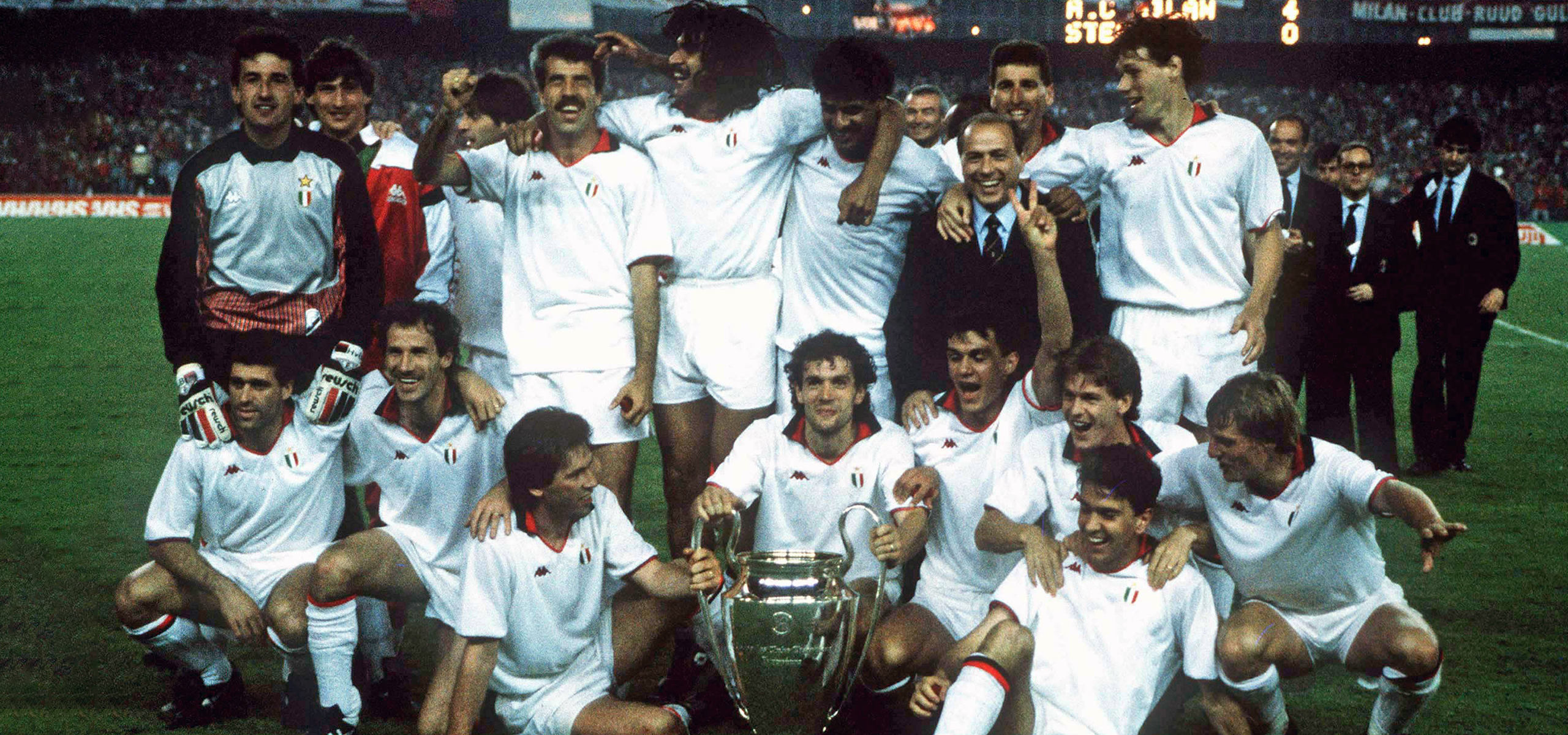 The victorious Rossoneri soccer team, clad in their iconic red-and-black striped uniforms, is captured in a moment of euphoria as they celebrate with the European Champion Clubs' Cup. The team's solidarity and joy are palpable as they pose with the prestigious trophy, embodying an era of unparalleled footballing dominance in Europe.