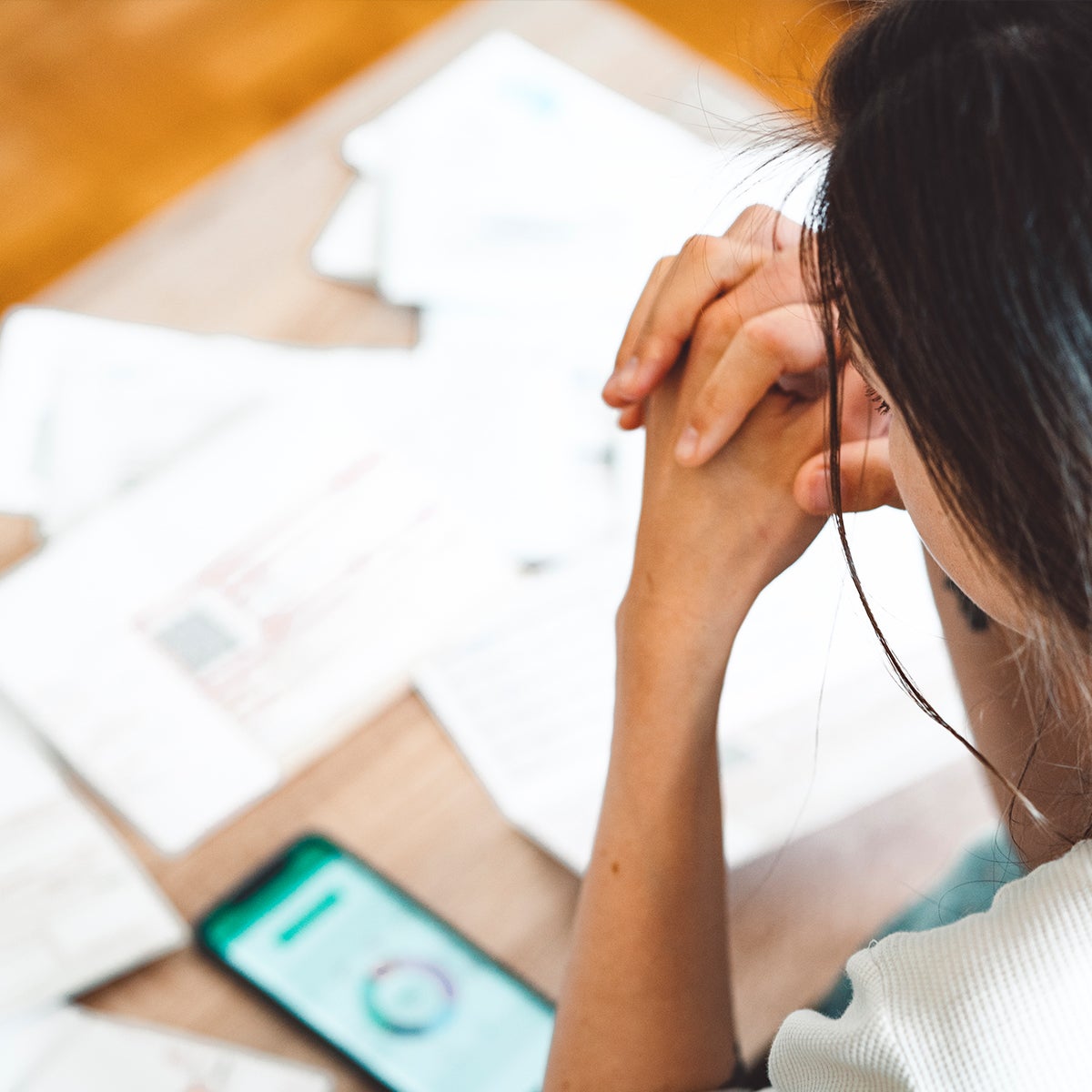 Person holding hands together looking at the desk with mobile phone