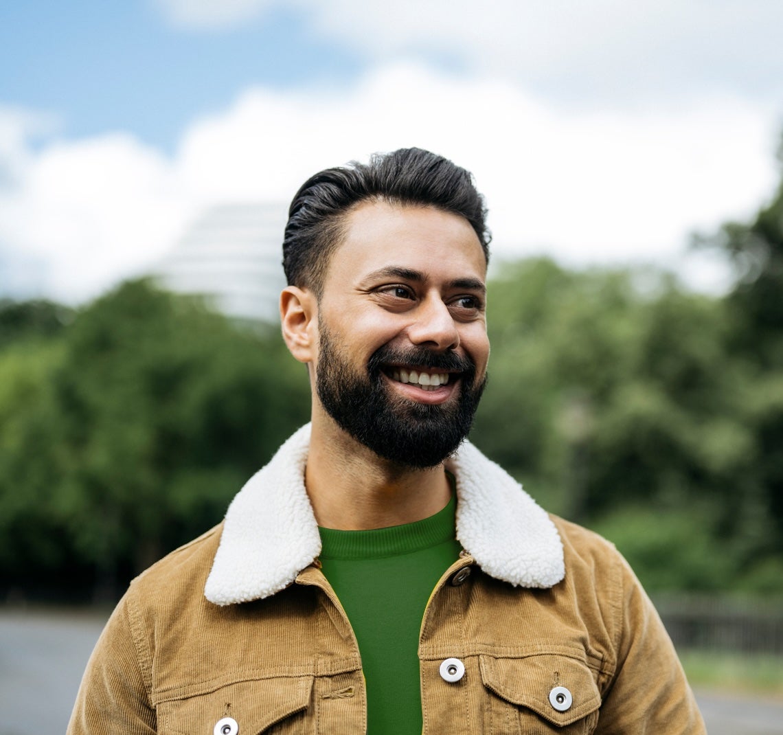 A man smiling outside with trees in the background