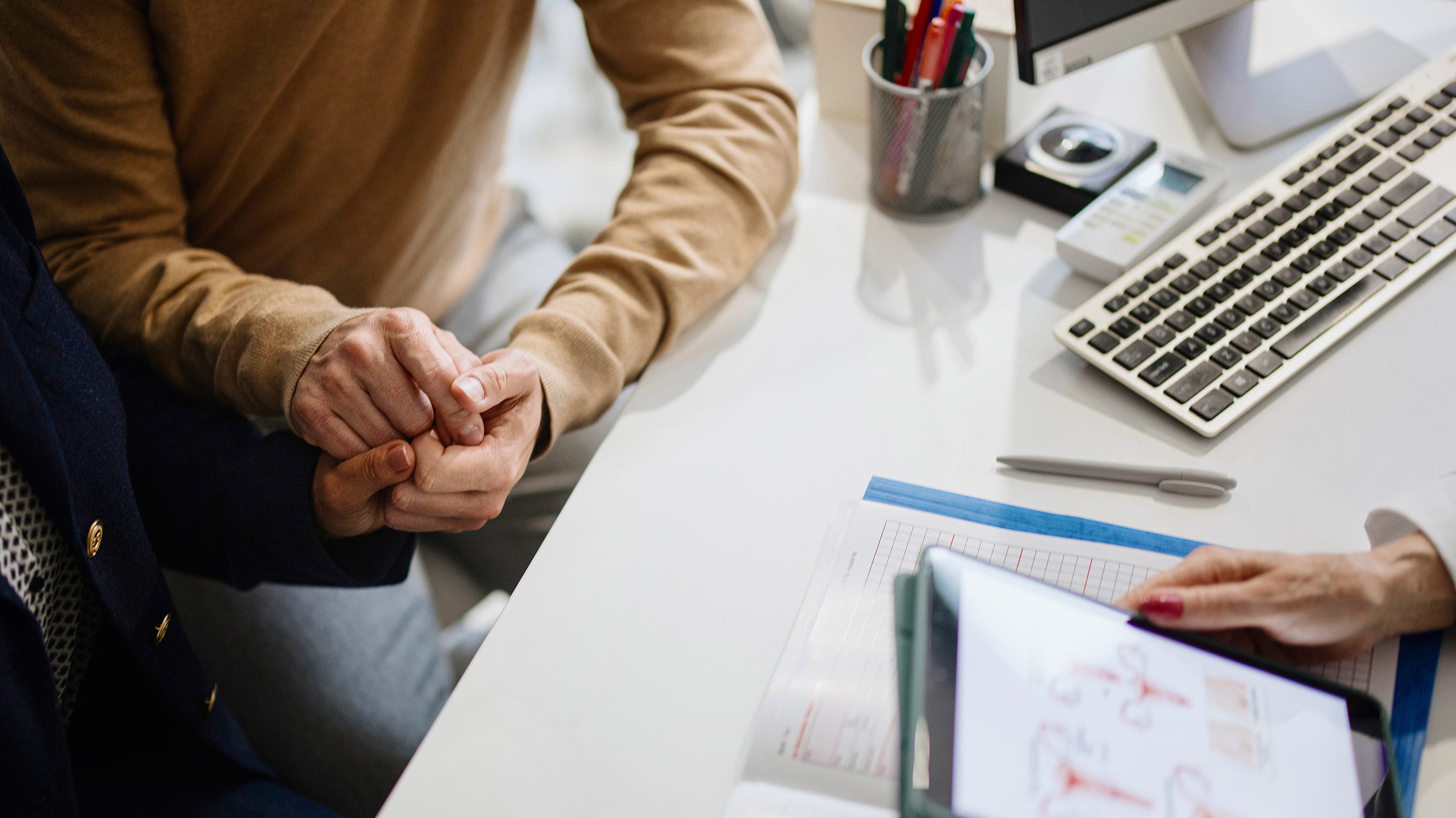 Person holding hands while being diagnosed by a doctor