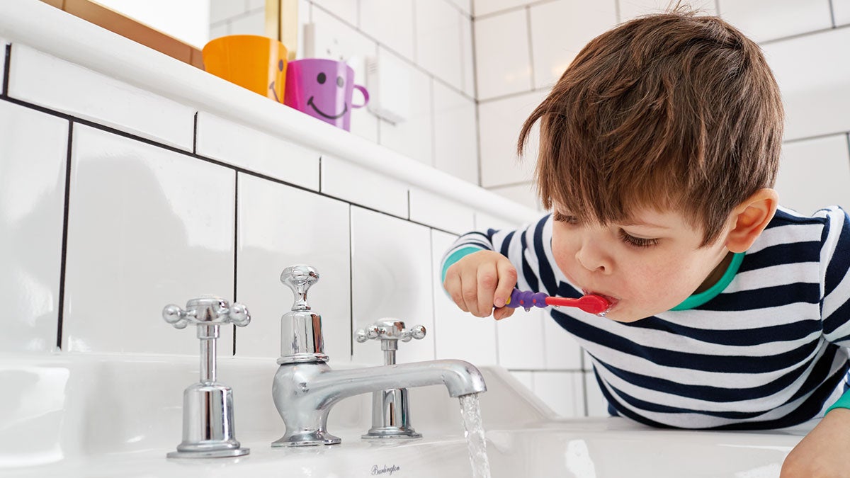 A child brushing his teeth in a sink