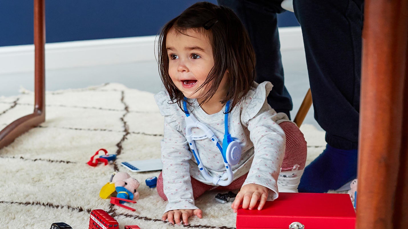 Young child playing with toys under table