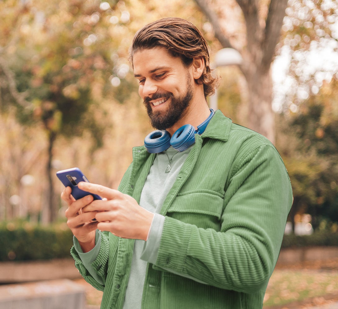 A man looking at his phone walking outside