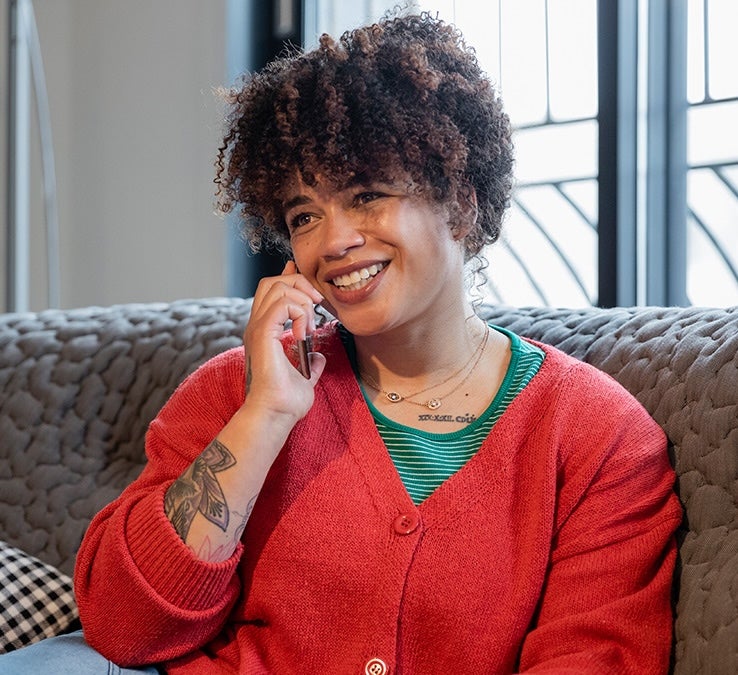 A woman sitting on a couch talking on a cell phone