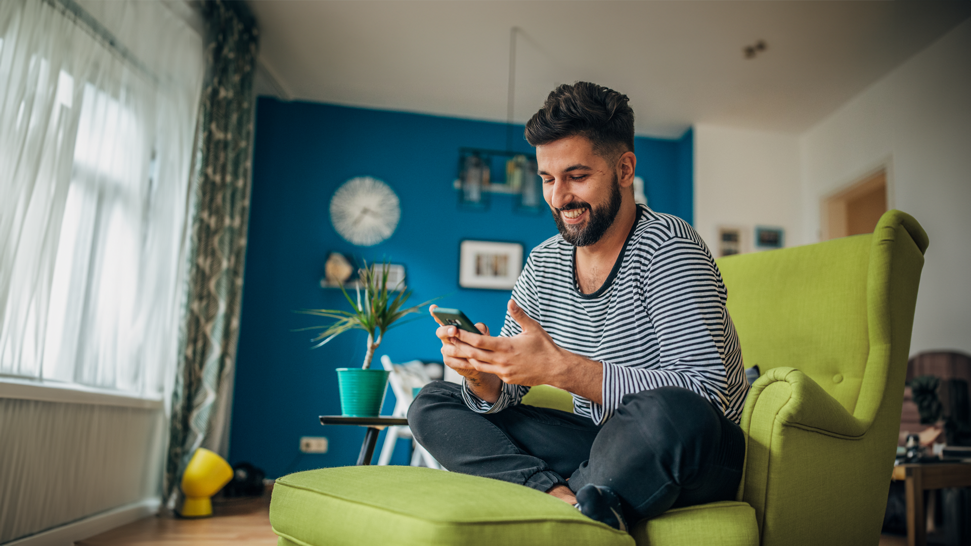 A man sitting on a green chair looking at his phone