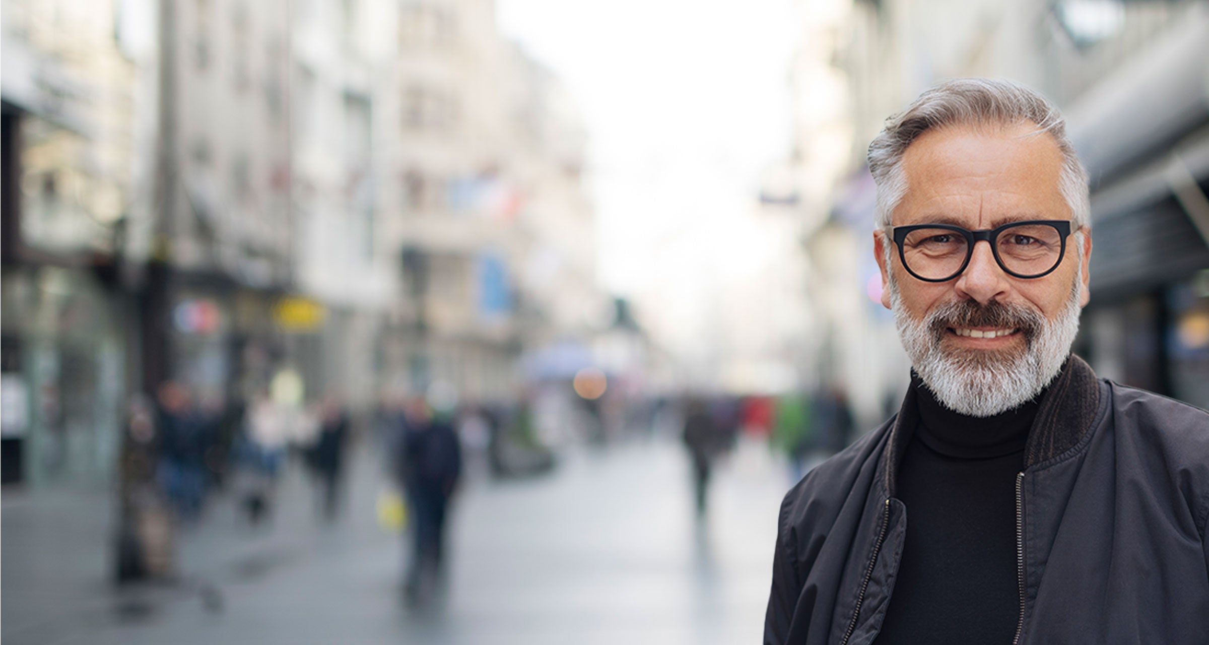 A man in glasses smiling wearing dark jacket