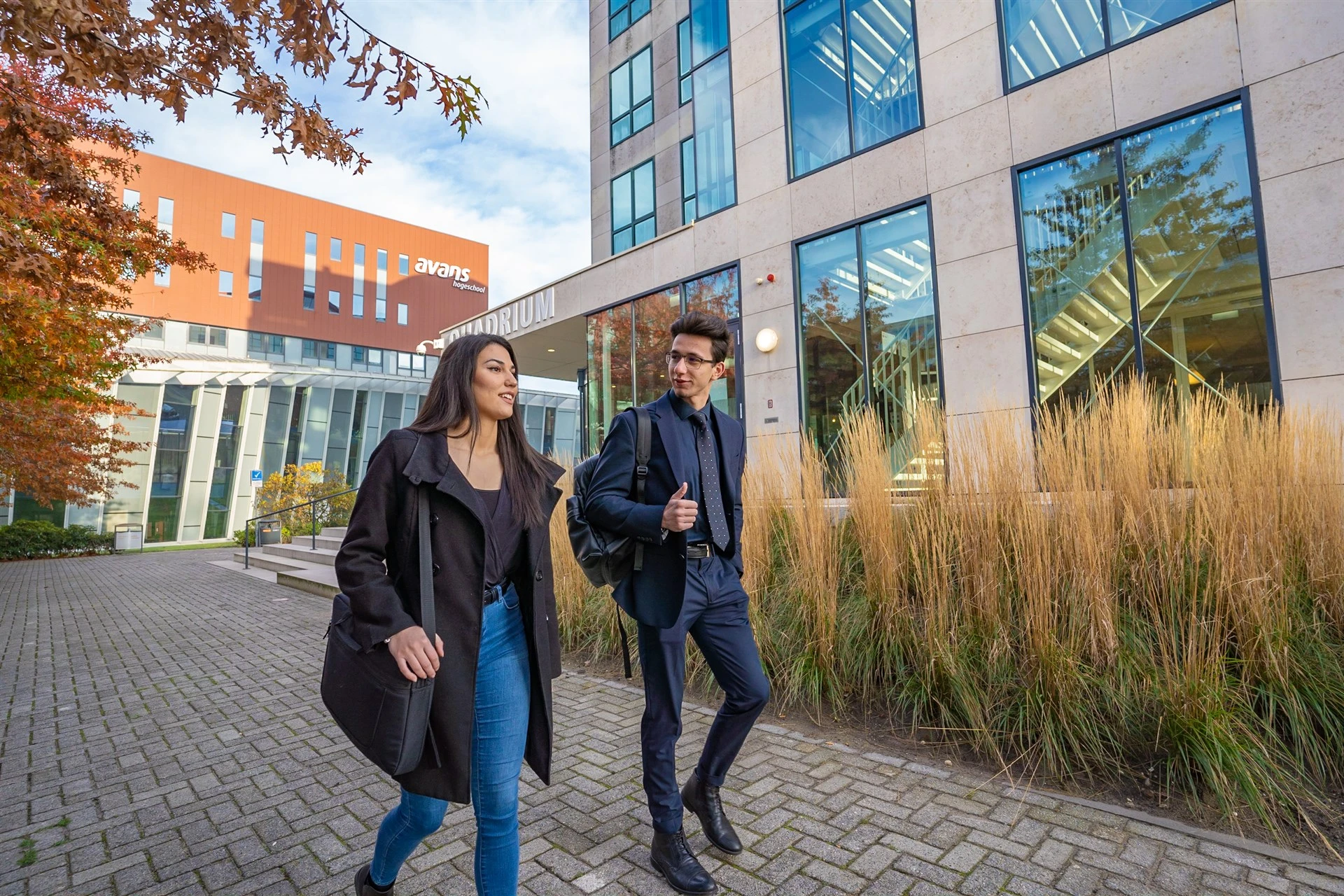 2 medewerkers van Avans lopen buiten voor het gebouw