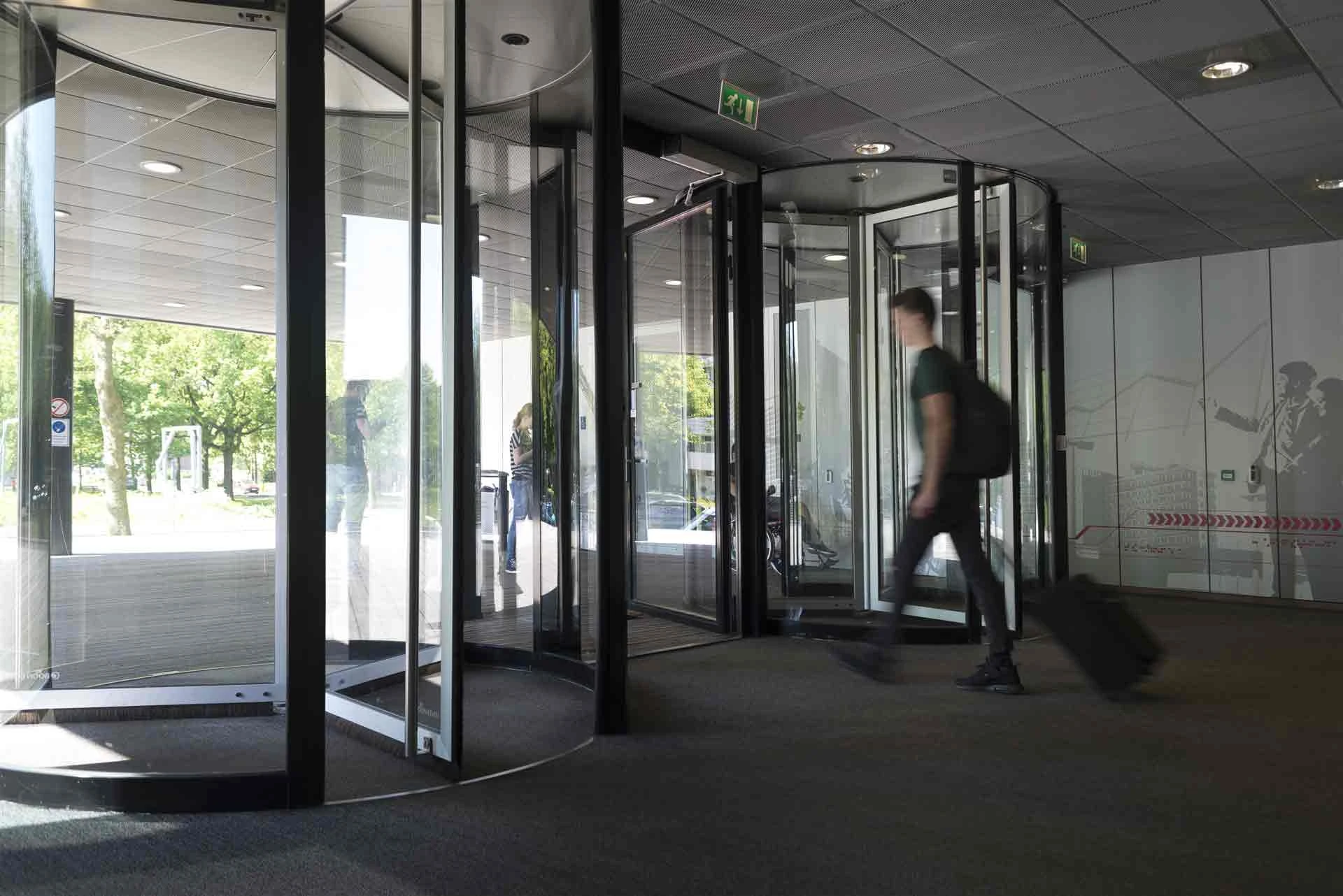 Student loopt door de draaideuren naar buiten van het Avans gebouw