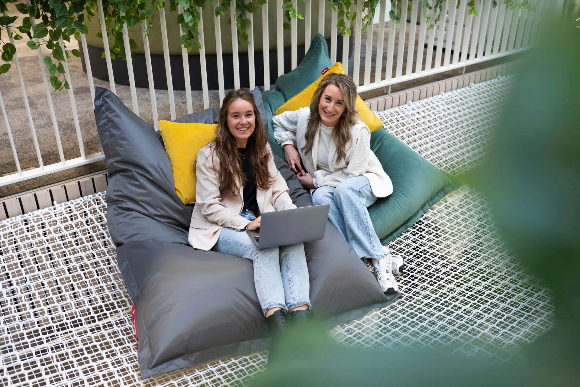 2 student are sitting together behind a laptop