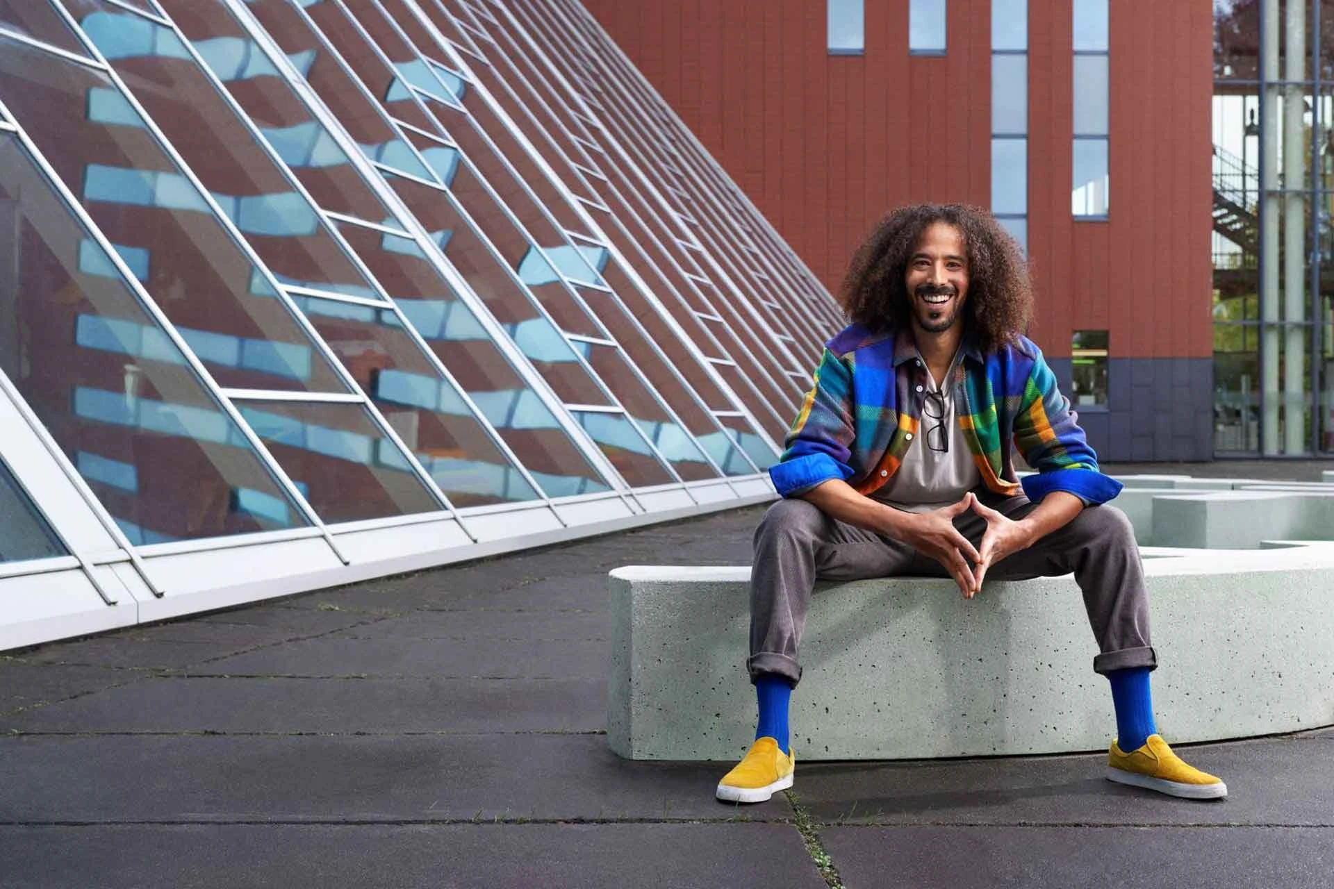A man sits in front of the Avans campus building in Breda