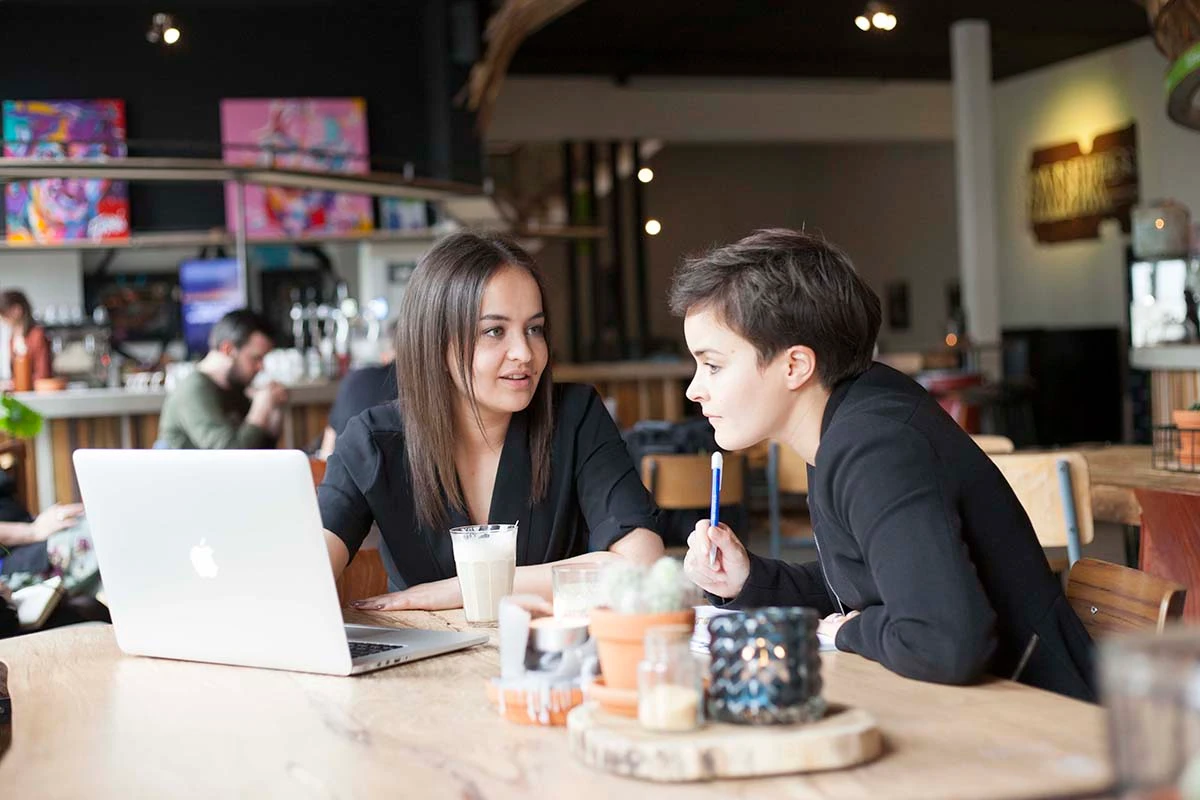2 oud studenten werken samen achter hun laptop in een koffiezaak