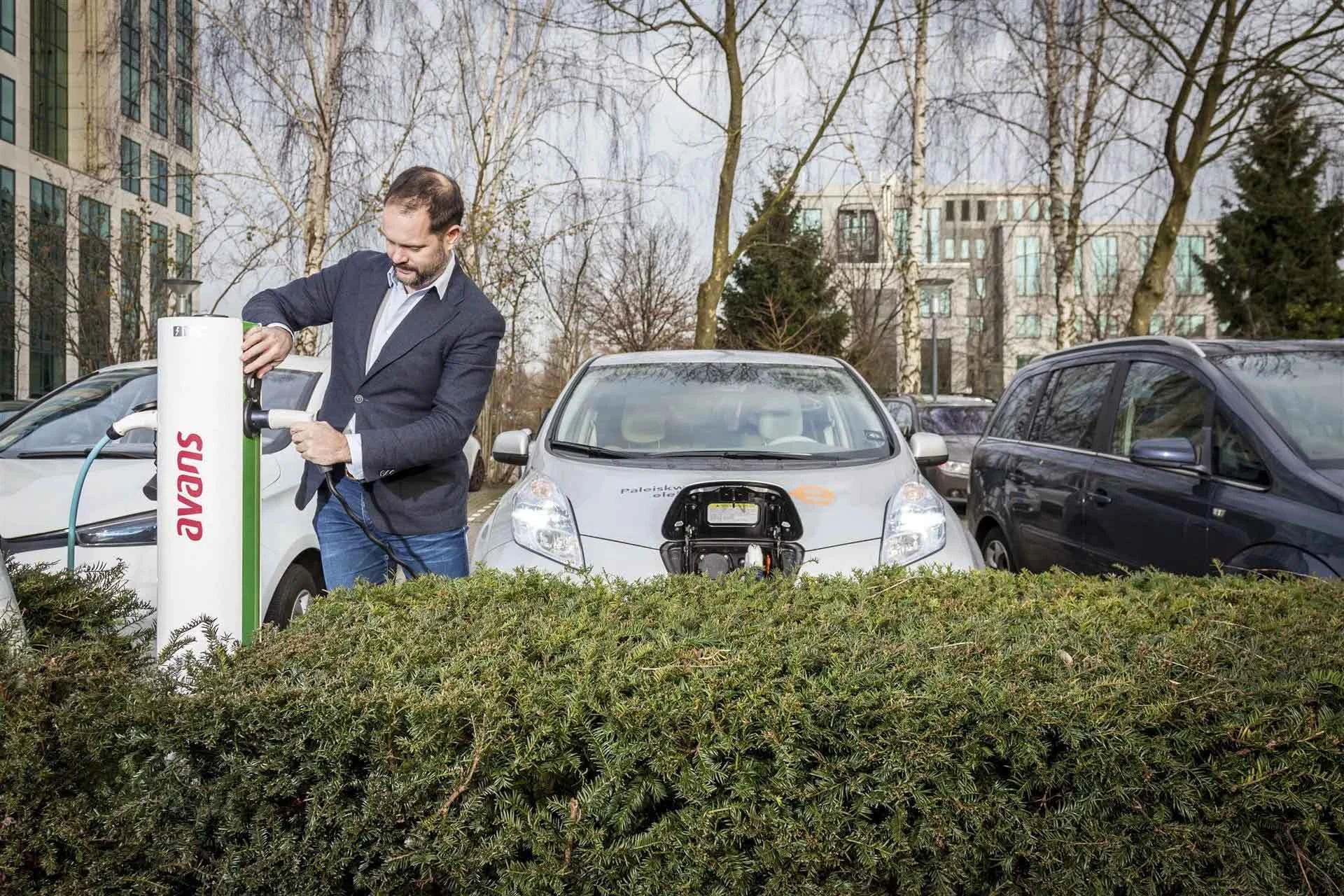 Man staat bij een laadpaal van Avans Hogeschool voor zijn elektrische auto