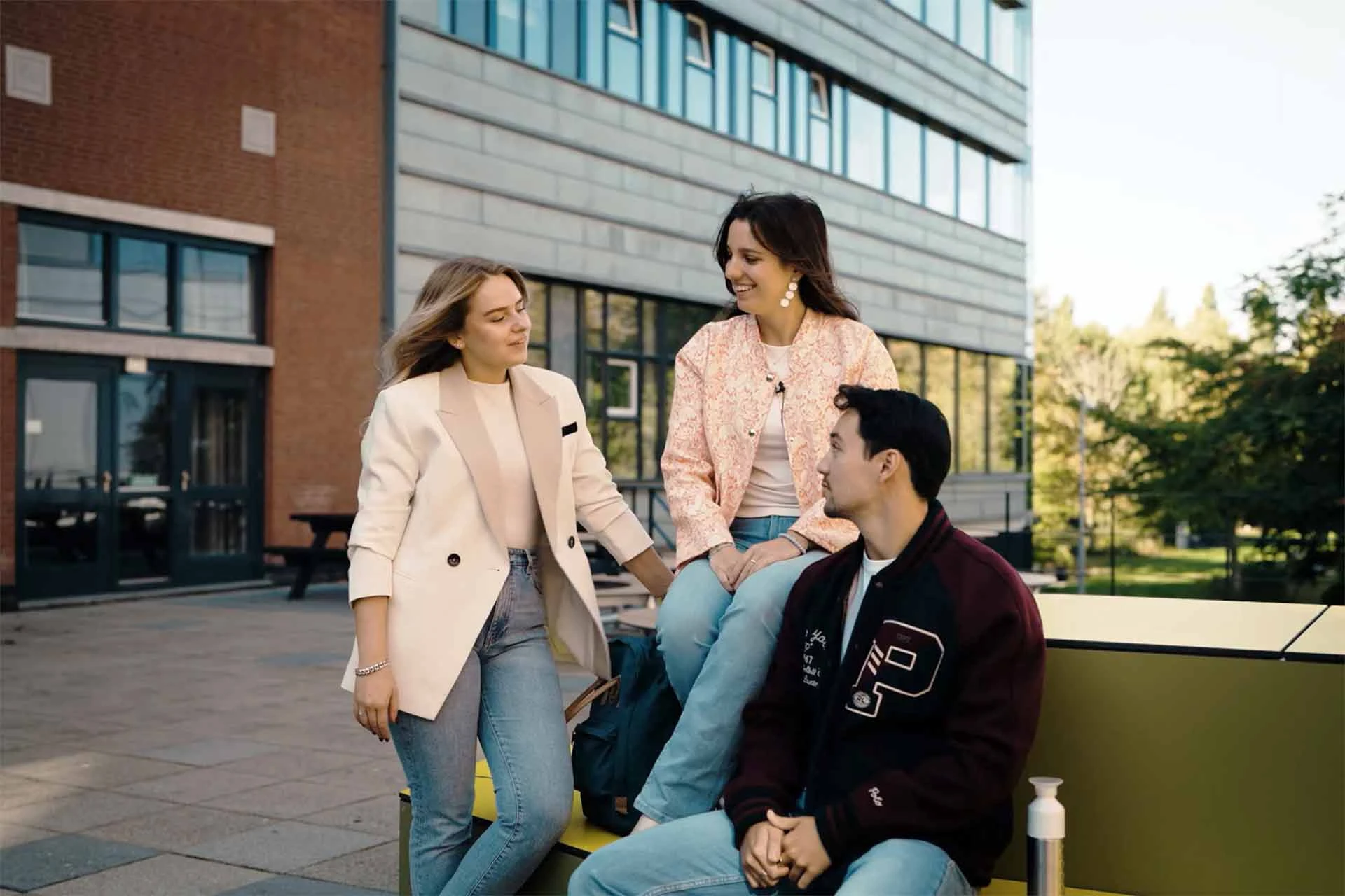 3 Avansstudenten zitten voor het Avans gebouw in Den Bosch