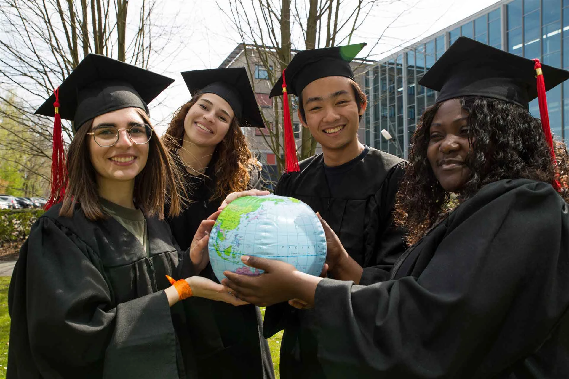 4 afgestudeerde Avans studenten met een wereldbol in hun handen