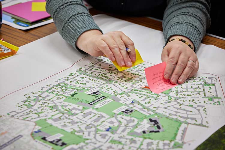 Person placing sticky notes on a neighbourhood map during a community planning and engagement workshop.