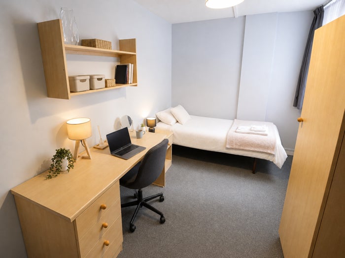 Single bedroom with bed, desk, shelving and wardrobe