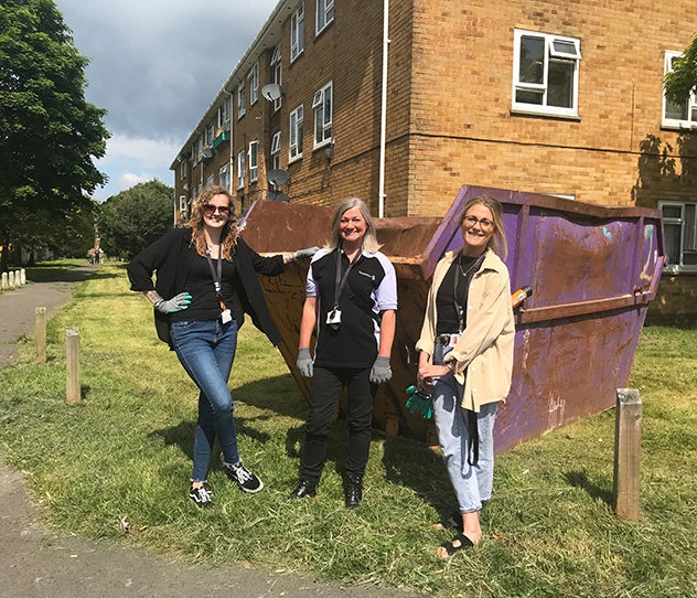 Three women standing in front of a skip