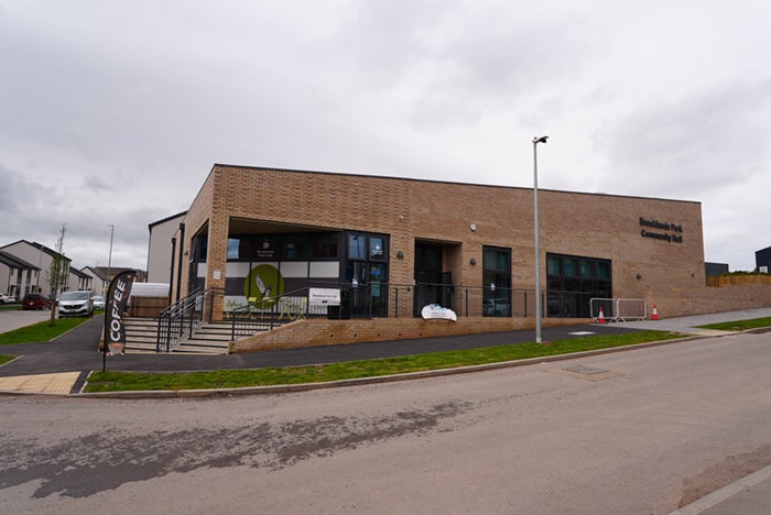 Exterior view of Brooklands Park Community Centre, a modern brick building with large windows beside a road.