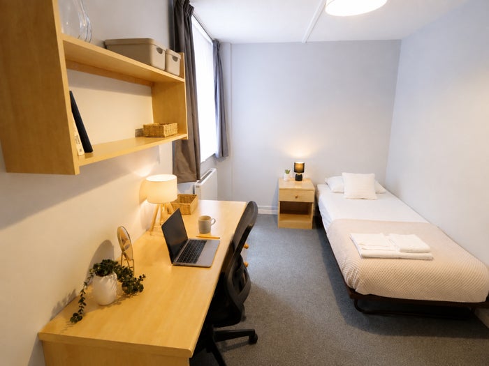 Single bedroom with desk, shelving and bed