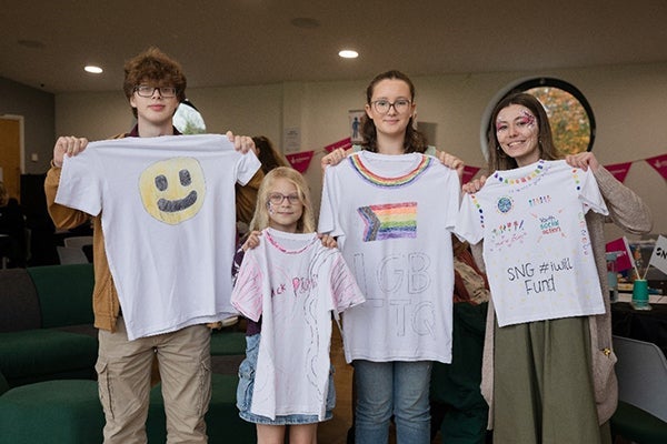 Young people posing for the camera as they hold decorated t-shirts