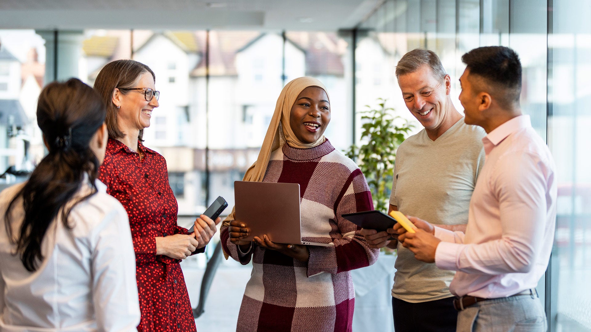 A group of colleagues laughing and chatting in an office